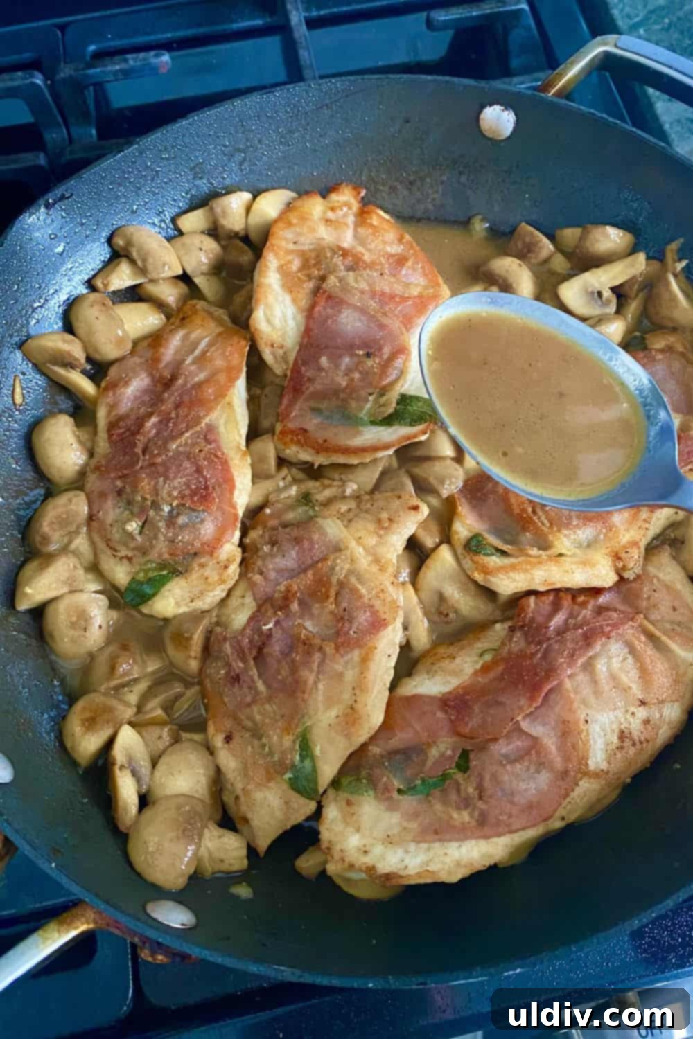 Prosciuttolu, Taze Adaçayı ve Marsala Mantar Soslu Tavuk 7 A close-up view of the rich Marsala mushroom sauce being poured over perfectly cooked chicken with prosciutto in a sauté pan.