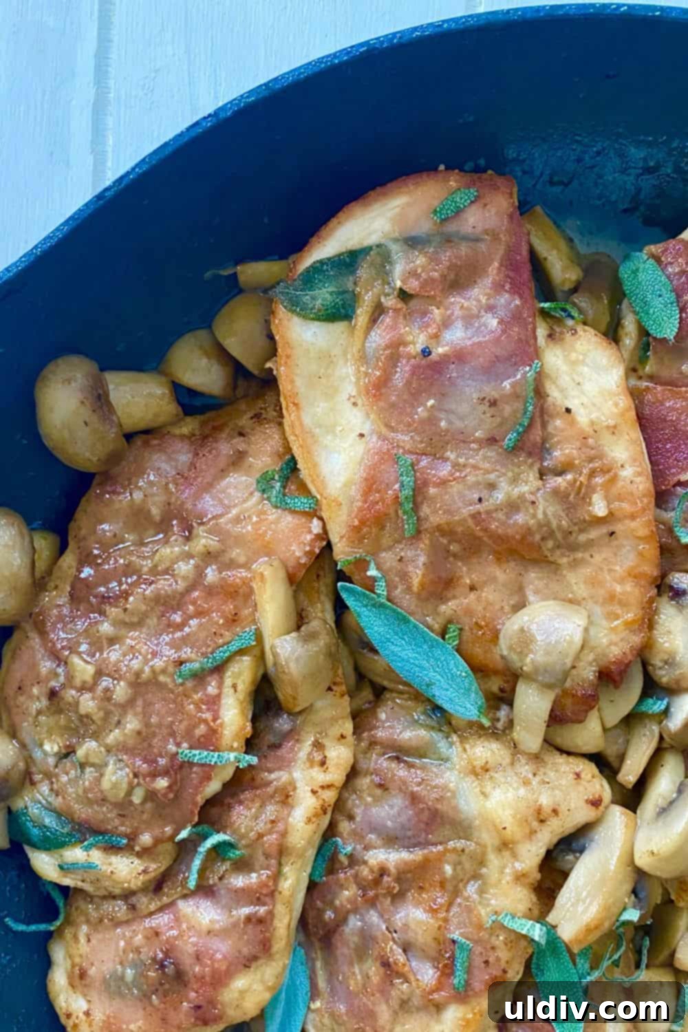 Prosciuttolu, Taze Adaçayı ve Marsala Mantar Soslu Tavuk 8 A sauté pan with golden-brown chicken and prosciutto, nestled among perfectly cooked mushrooms and fresh sage.