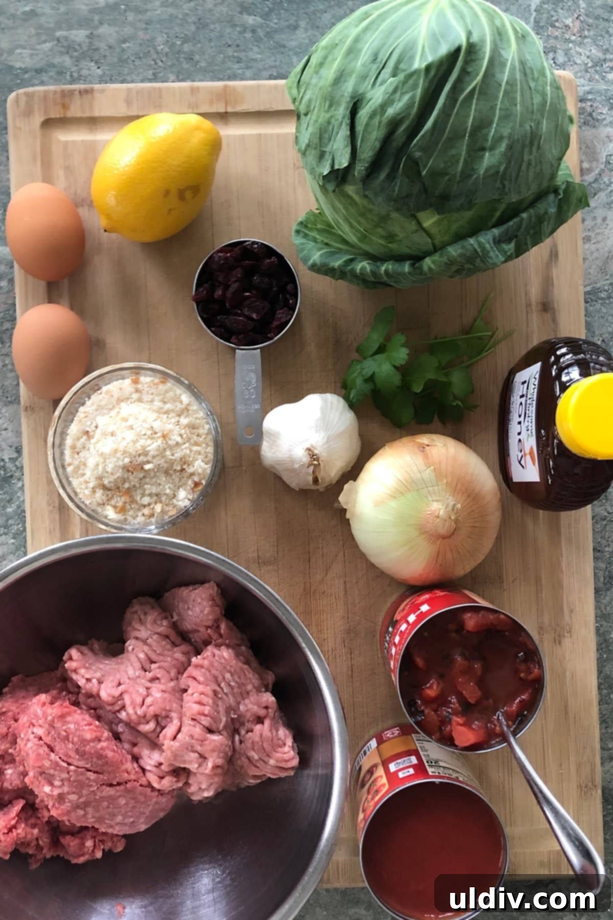 Cabbage Roll Meatball Bake 3 Fresh ingredients laid out: cabbage, eggs, honey, onion, garlic, dried cranberries, ground beef and turkey, canned tomatoes, ready for making Cabbage Roll Meatballs