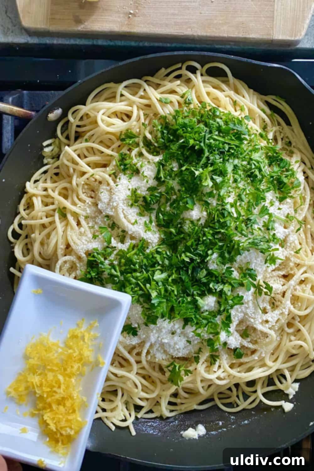 Creamy Garlic Parmesan Noodles 8 Sprinkling vibrant lemon zest over a serving of buttered noodles with Parmesan, enhancing the dish with fresh citrus notes.