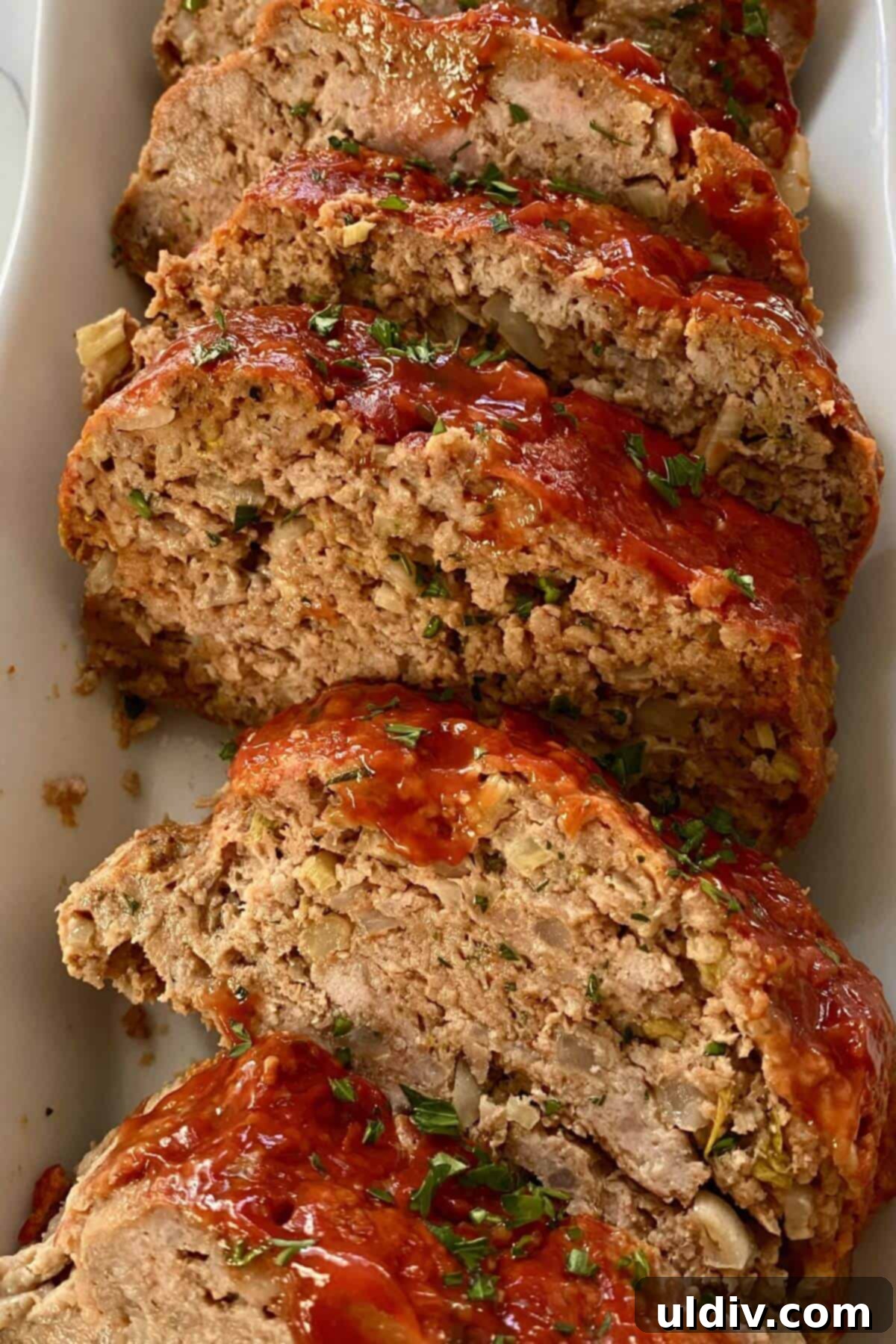 The Ultimate Mom's Meatloaf 2 Slices of mom's meatloaf in a white serving dish.