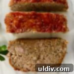 Slices of perfectly cooked meatloaf on a white marble cutting board.