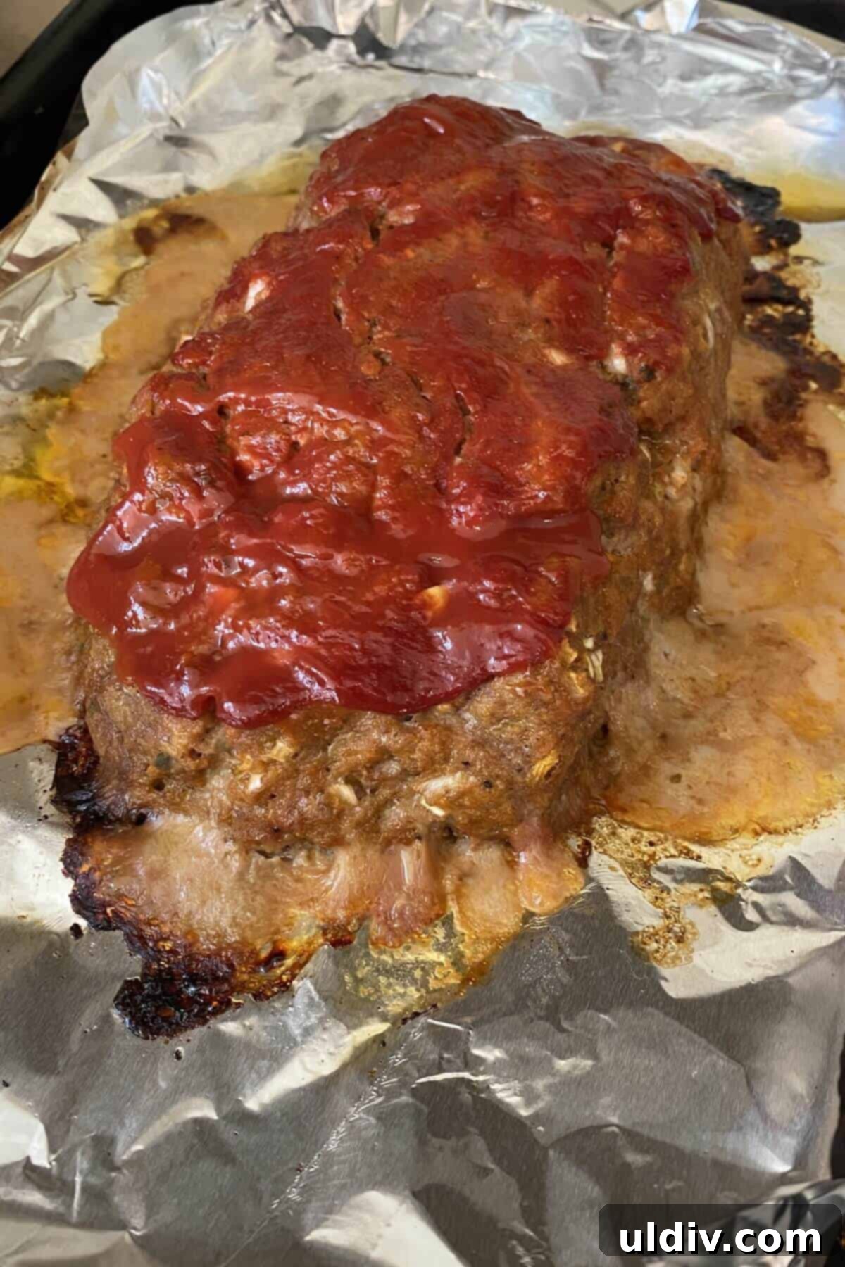 Mom's Legendary Meatloaf Recipe 6 A freshly baked meatloaf resting on a foil-lined baking sheet, glistening with its ketchup glaze.