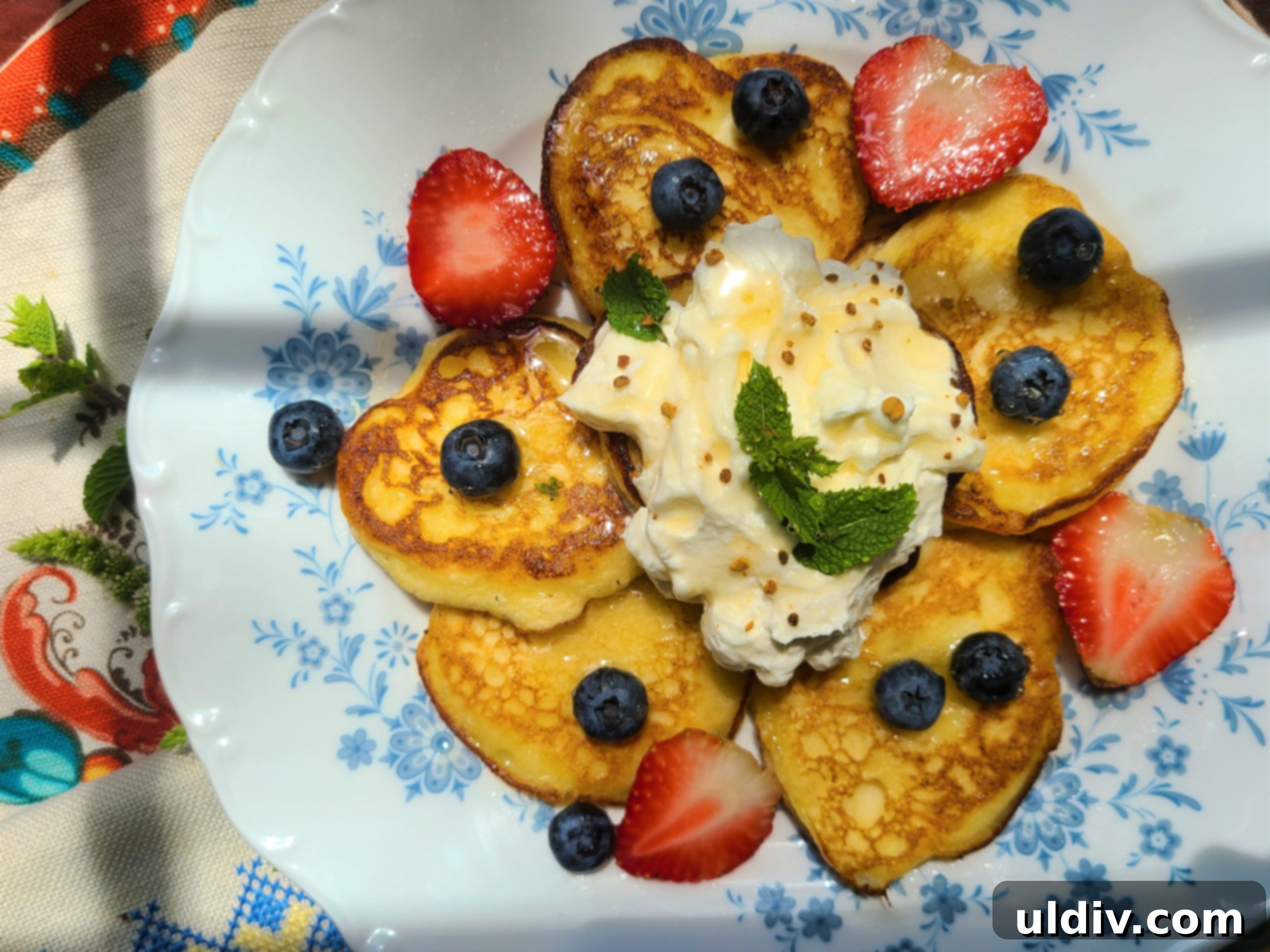 A stack of fluffy lemon ricotta pancakes drizzled with maple syrup and topped with fresh blueberries.