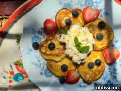 A glass of refreshing strawberry mocktail alongside a plate of lemon ricotta pancakes.