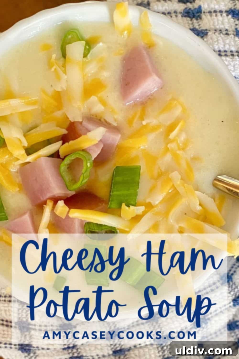 30-Minute Easy Cheesy Ham and Potato Soup 12 A generously sized bowl of rich, cheesy ham and potato soup, presented on a wooden surface with a blue and white patterned napkin, exuding warmth and homeliness.
