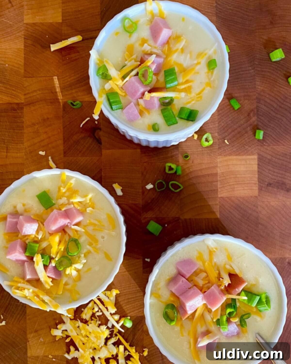 30-Minute Easy Cheesy Ham and Potato Soup 7 Three inviting bowls of easy ham and potato soup, garnished with additional sour cream, cheese, ham, and fresh scallions, ready to be enjoyed.