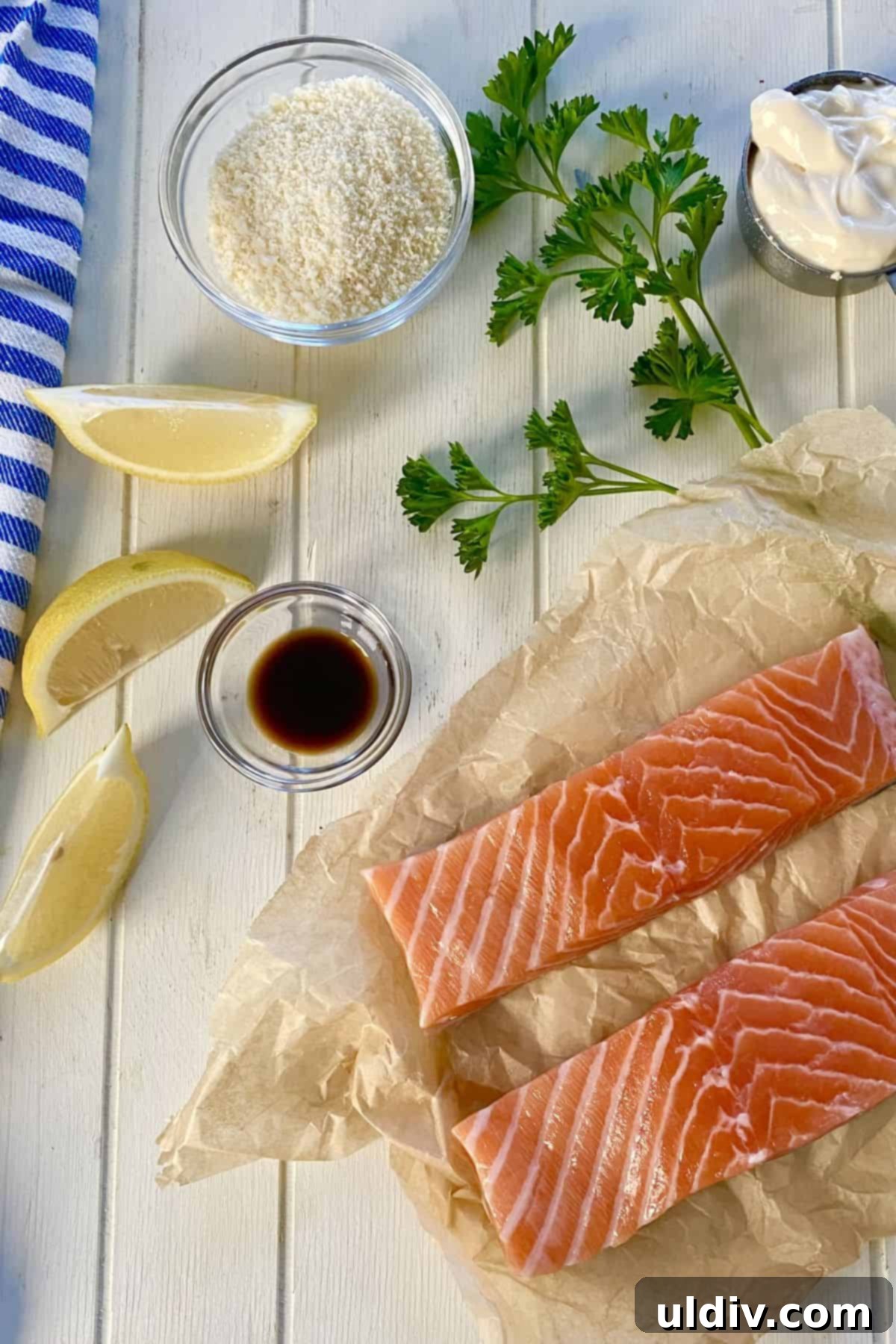 Savory Roasted Salmon Caesar 3 A vibrant flat lay of fresh ingredients for Roasted Salmon Caesar: salmon fillets, bright yellow lemon, creamy mayonnaise, grated Parmesan cheese, fresh green parsley, and a bottle of Worcestershire sauce.