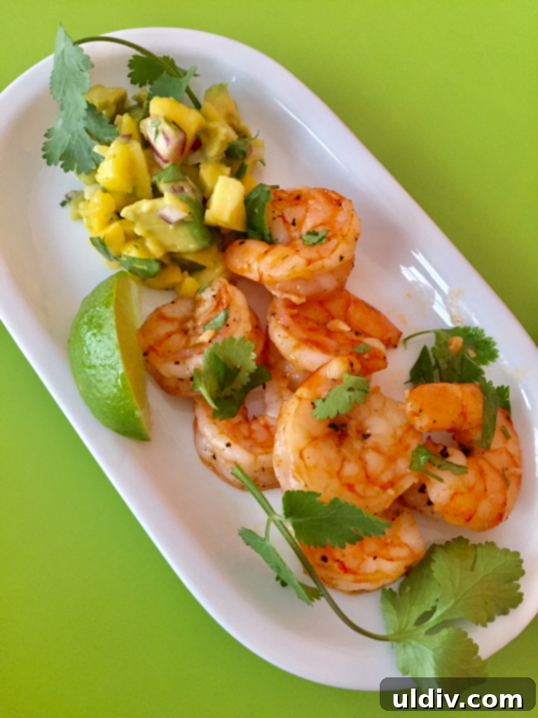 Zesty Tequila Lime Shrimp with Tropical Mango Avocado Salsa 2 A white platter with cilantro lime tequila with mango salsa.