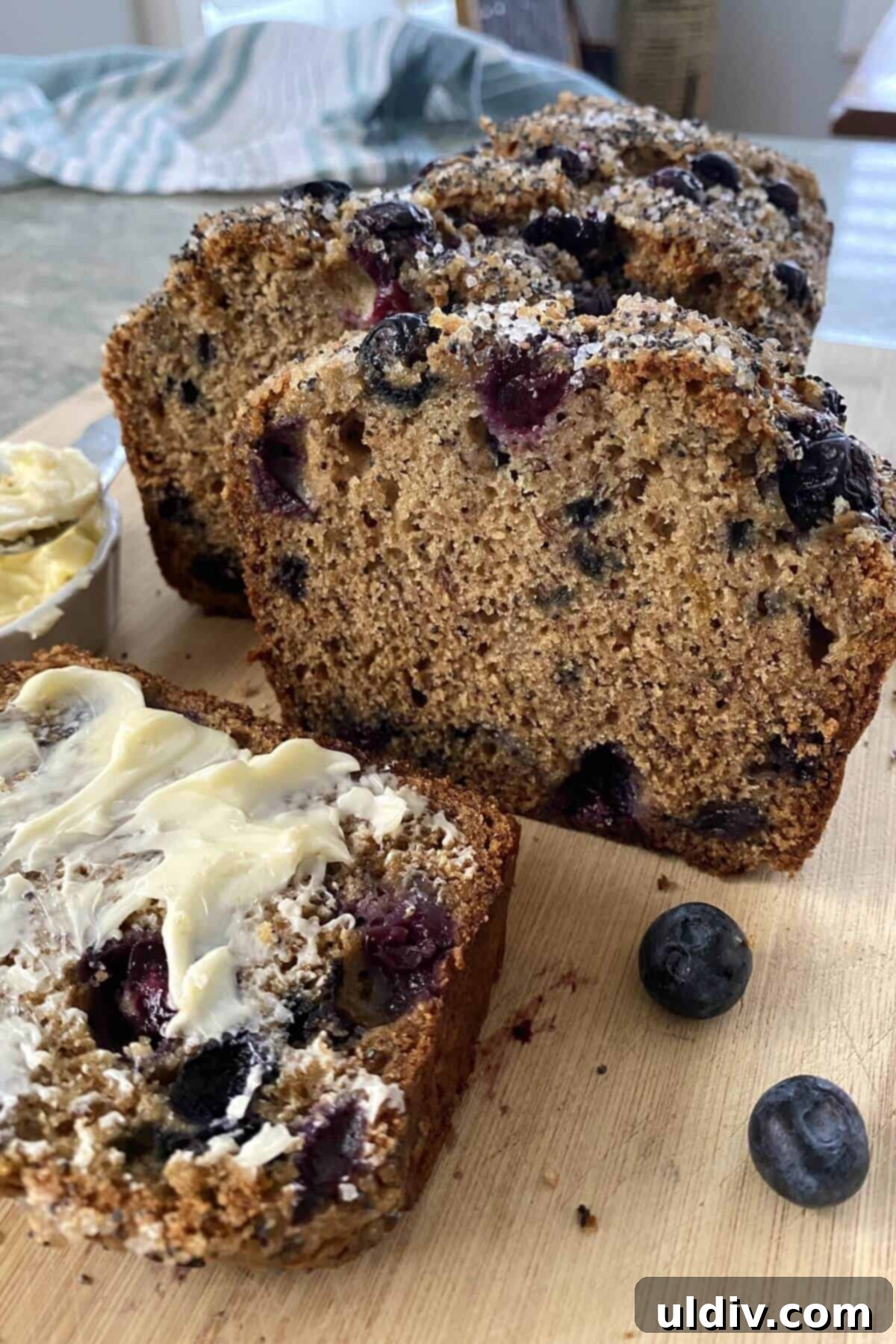 Mediterranean Olive Oil Banana & Blueberry Loaf 2 sliced olive oil banana bread with blueberries and butter.