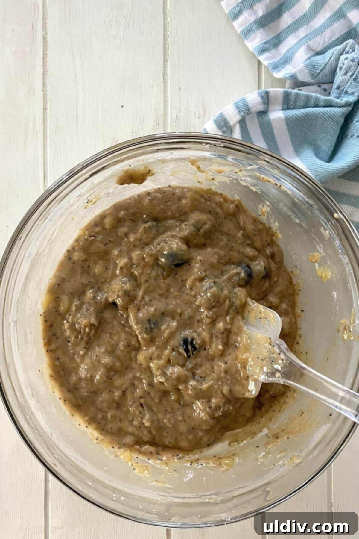 Mediterranean Olive Oil Banana & Blueberry Loaf 6 olive oil banana bread batter in a bowl with a spatula.