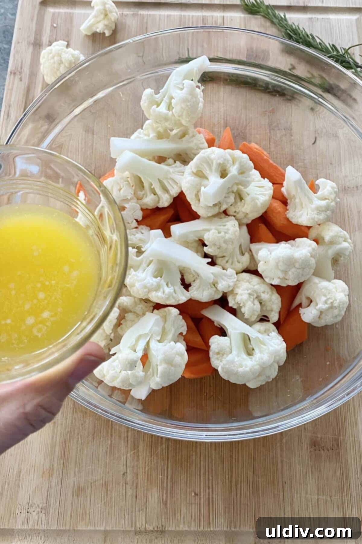 Honey-Glazed Roasted Carrots and Cauliflower with Tangy Goat Cheese 4 Adding melted butter to carrots and cauliflower in a mixing bowl.