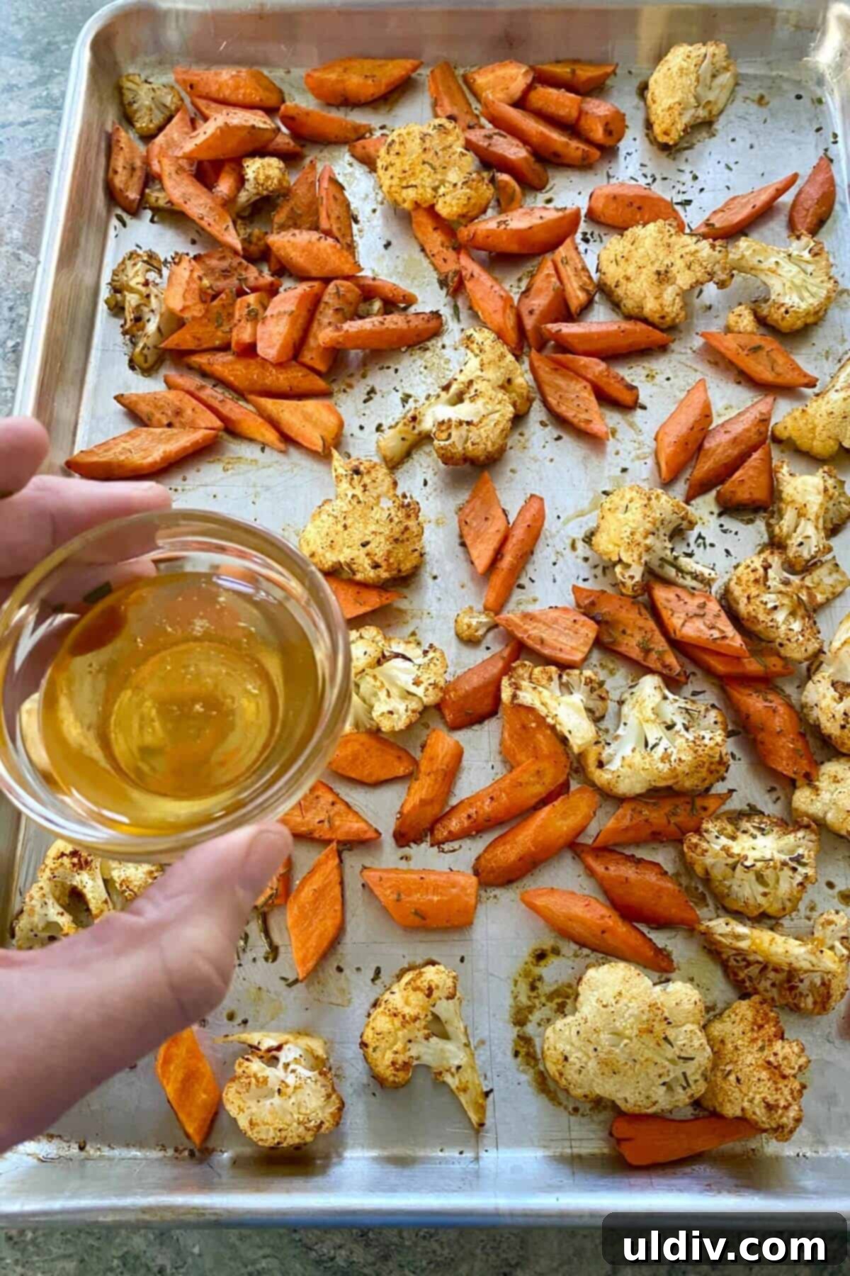 Honey-Glazed Roasted Carrots and Cauliflower with Tangy Goat Cheese 6 Drizzling honey over roasted carrots and cauliflower on a baking sheet.