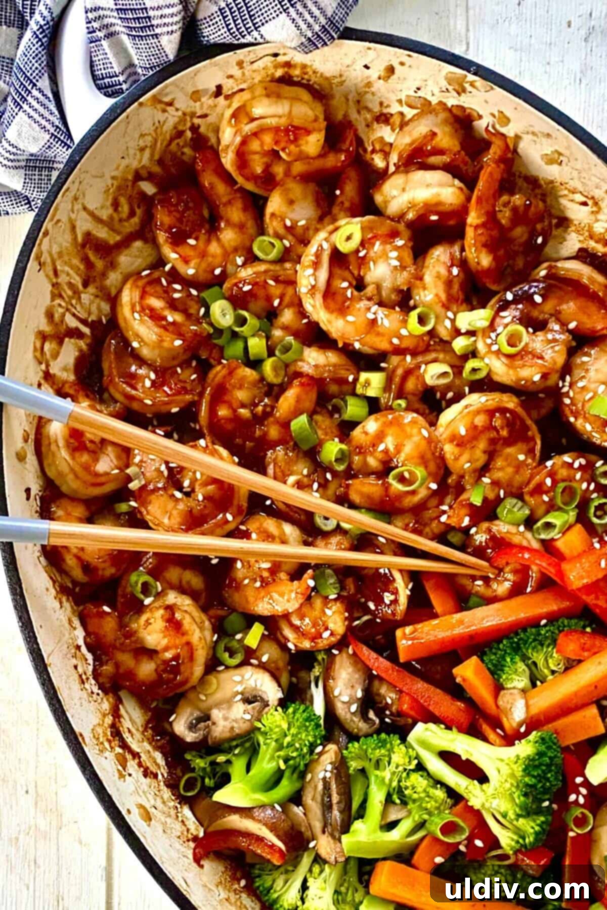 Sizzling Hibachi Shrimp with Colorful Vegetable Medley 2 large white pan with hibachi shrimp and vegetables with chopsticks.