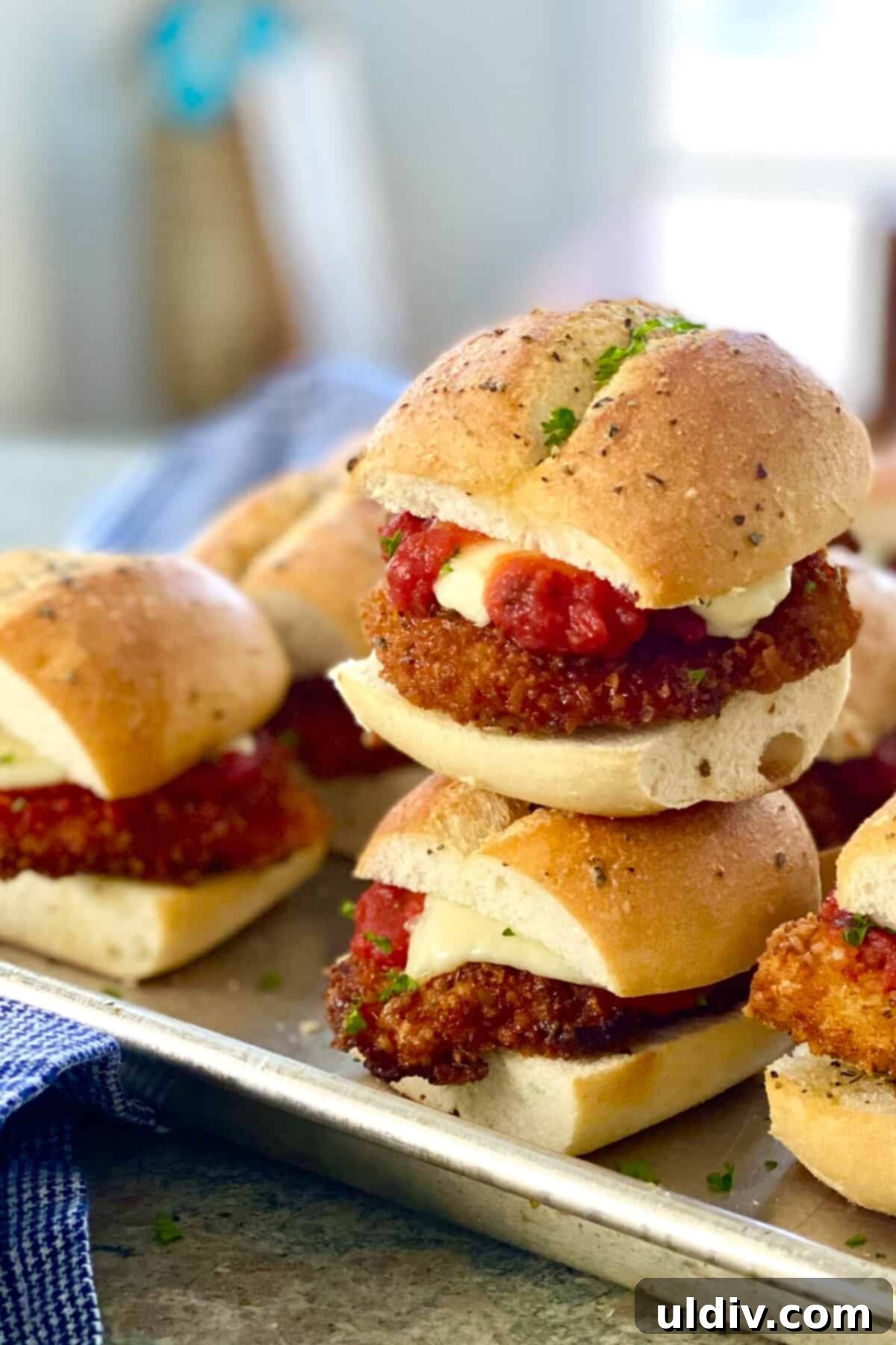 Bite-Sized Chicken Parm Sliders 2 Two mini chicken parm sandwiches stacked on top of each other, showcasing melted cheese and golden chicken.
