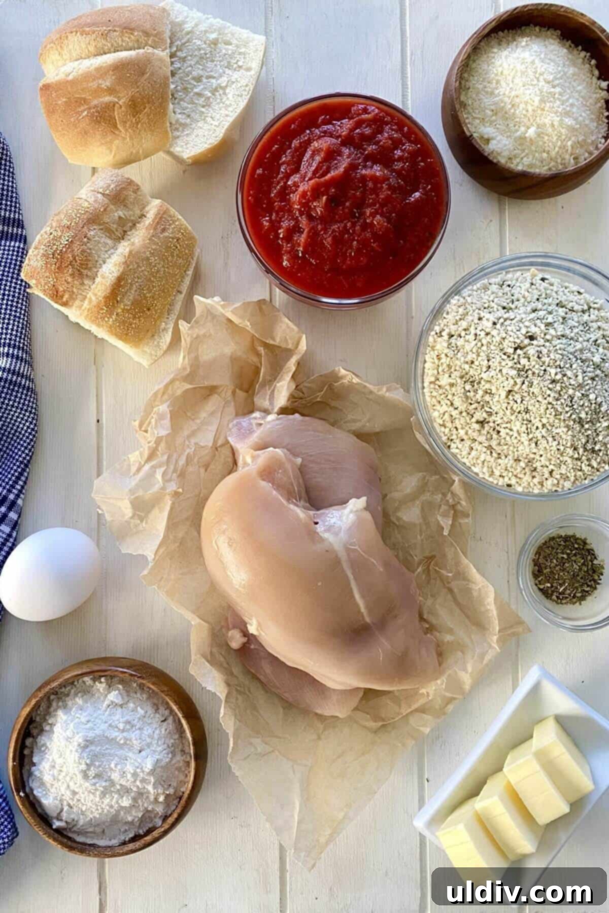 Mini Chicken Parm Sliders 3 Chicken breast, marinara sauce, panko, egg, flour, and rolls arranged on a wooden board, ready for sandwich preparation.
