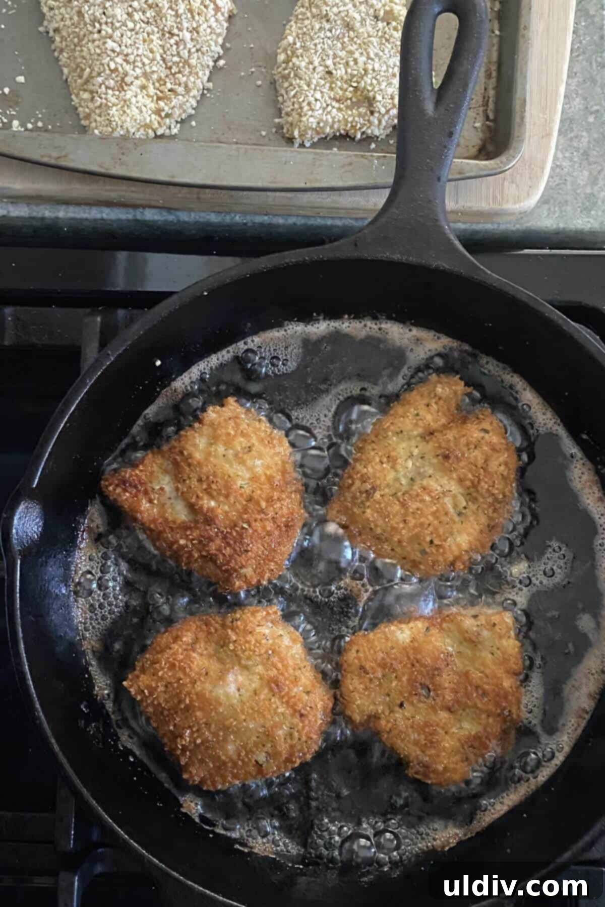 Mini Chicken Parm Sliders 5 Frying chicken in a cast iron skillet, golden brown and crispy.