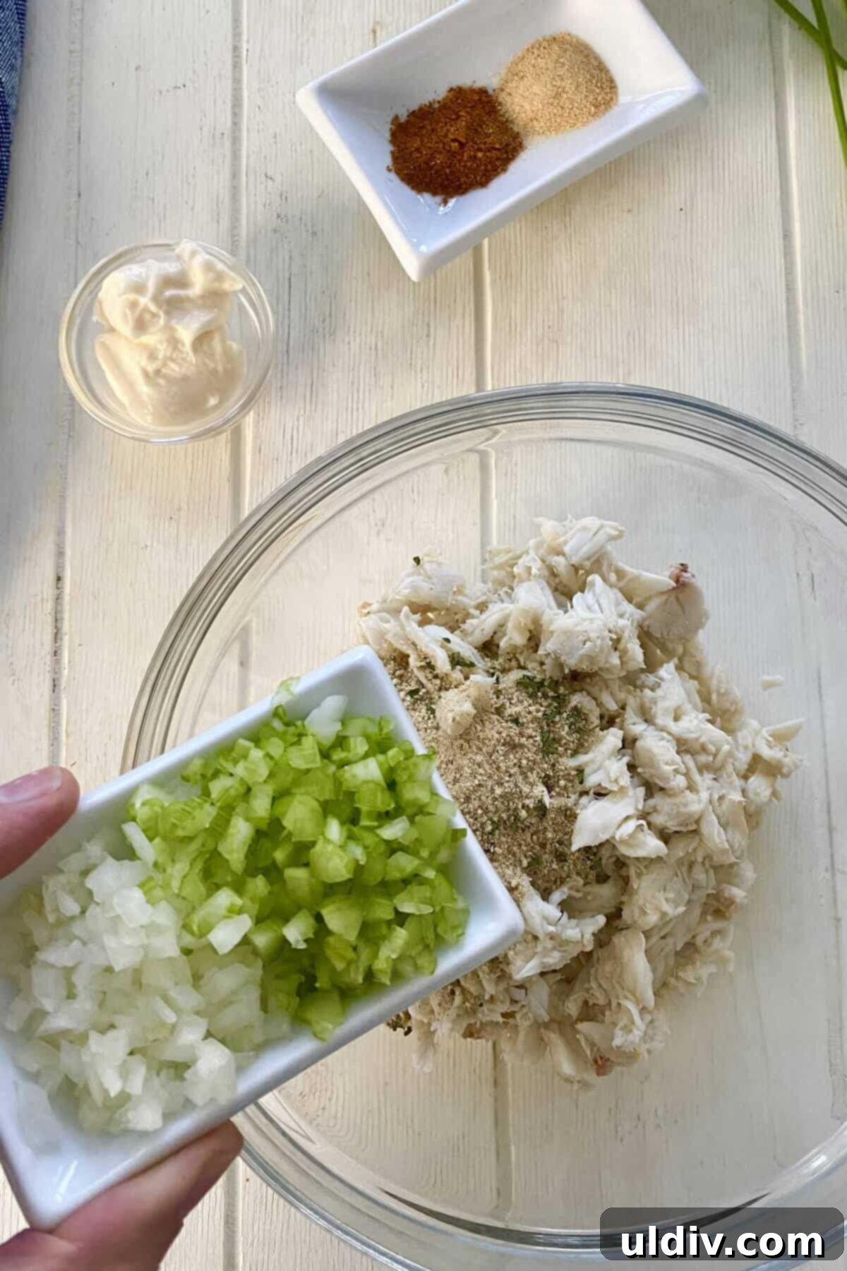 Crab-Filled Salmon Perfection 5 Finely chopped celery and onion being added to a bowl of lump crab meat, preparing for the stuffing mixture.