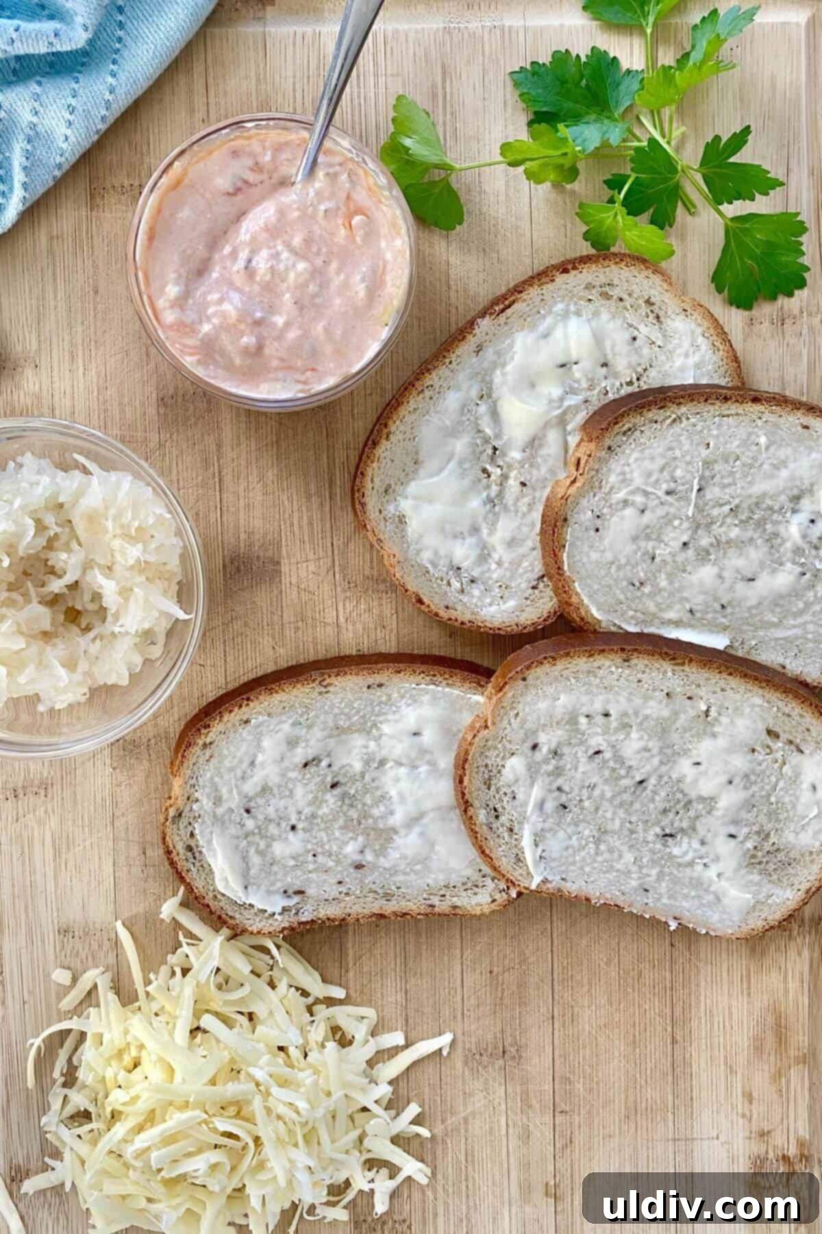 Wild Cod Reuben: Dressed in 30 Seconds 7 An assembly line of fish reuben ingredients: buttered rye bread, a pile of sauerkraut, and a mound of shredded Swiss cheese on a cutting board.