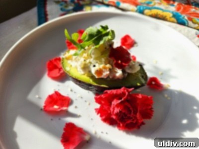 2024's Easiest Super Bowl Snacks 3 Two vibrant avocado halves, generously stuffed with a creamy salad made of potatoes, carrots, peas, and corn, drizzled with olive oil and seasoned with everything bagel seasoning, garnished with delicate edible flowers.