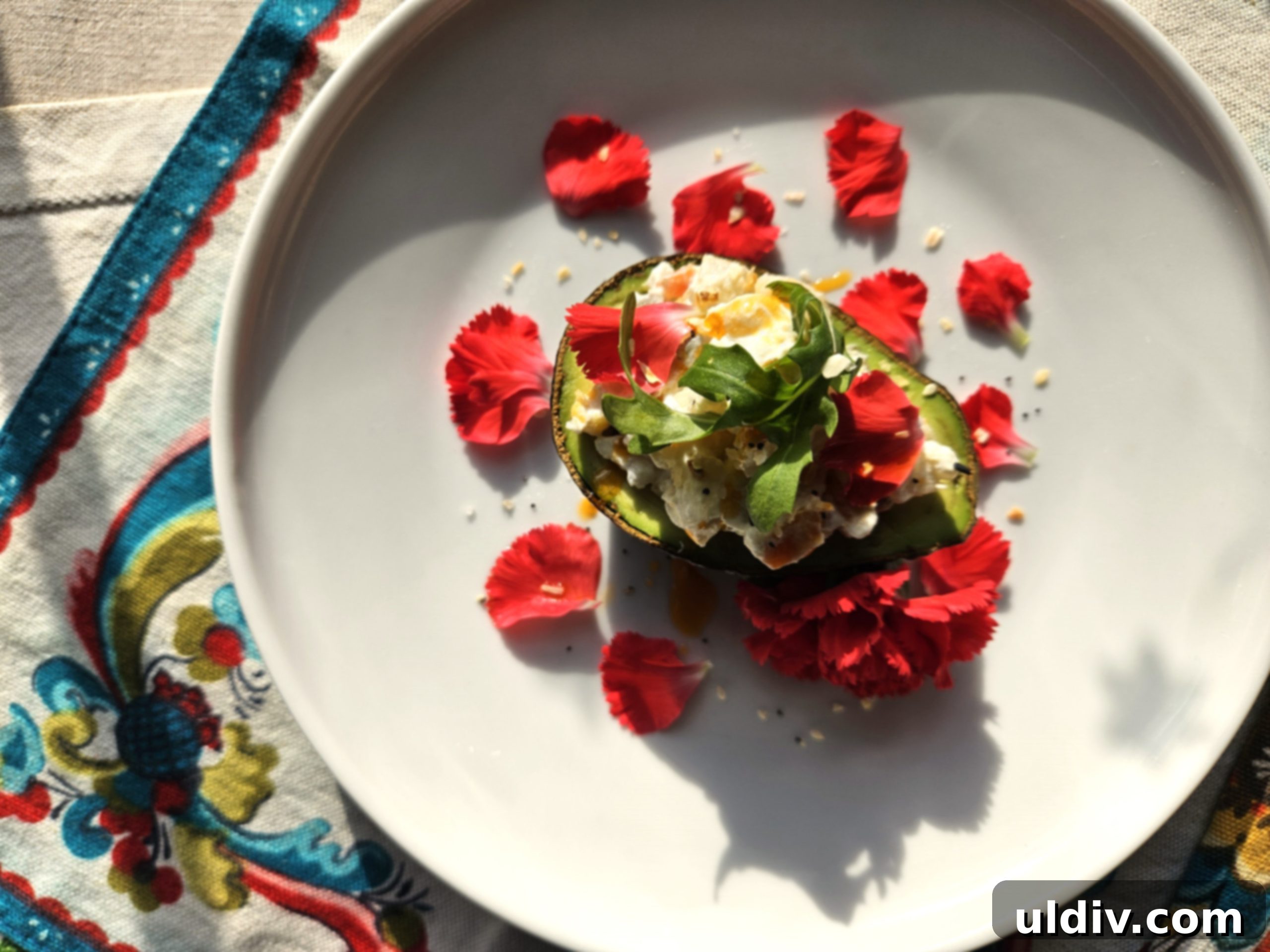 2024's Easiest Super Bowl Snacks 4 A close-up of a beautifully presented stuffed avocado on a plate, showcasing the creamy salad filling, fresh herbs, and colorful edible flowers, ready to be enjoyed.