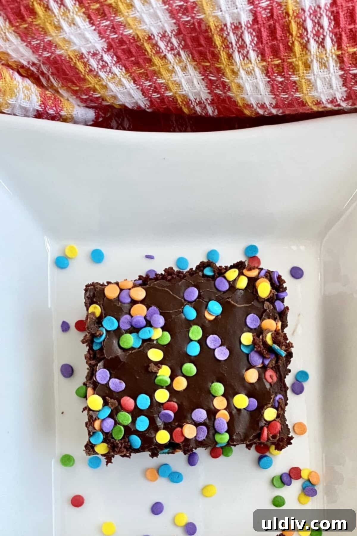 A delicious slice of chocolate Texas Sheet Cake with colorful sprinkles, paired with a glass of milk.