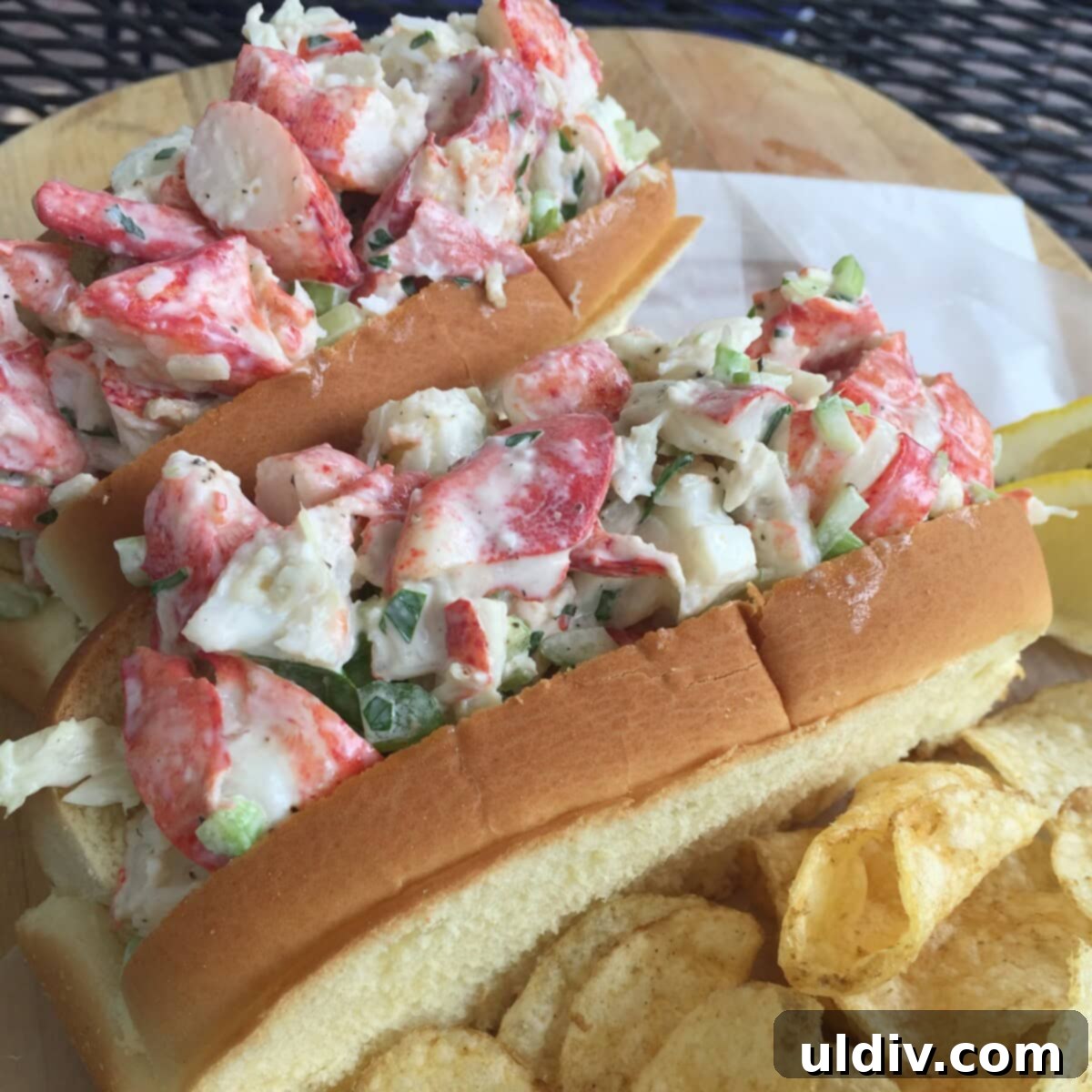 The Art of the Lobster Roll 2 Two generously filled cold lobster rolls served with crispy potato chips, inviting a delightful summer meal.