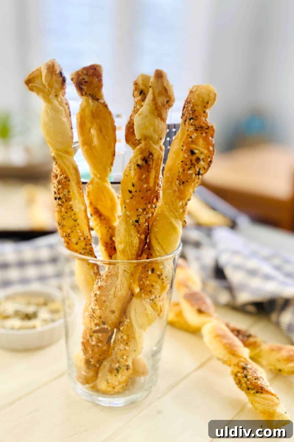 Flaky Everything Bagel Cheese Twists 2 Crispy Everything Bagel Puff Pastry Cheese Twists elegantly arranged in a glass, ready for serving.