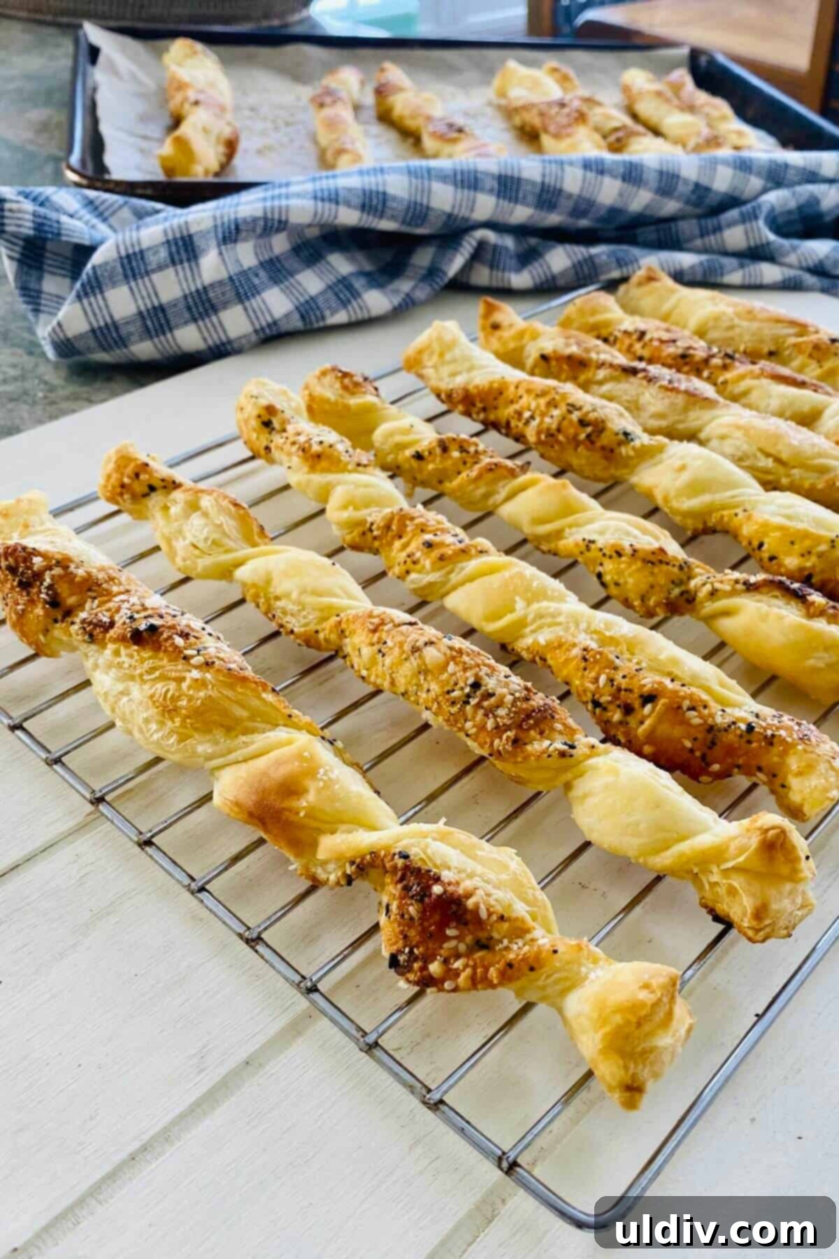 Flaky Everything Bagel Cheese Twists 4 Freshly baked puff pastry cheese twists cooling on a wire rack.