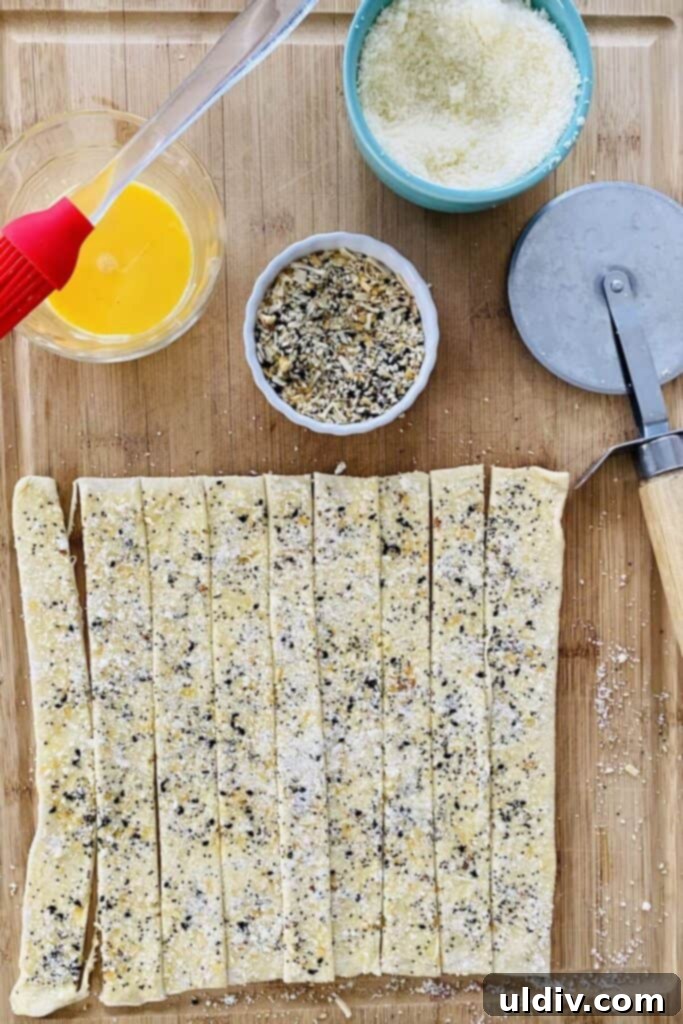 Crispy Everything Bagel Cheese Spirals 7 Puff pastry strips cut and ready to be twisted into cheese breadsticks.