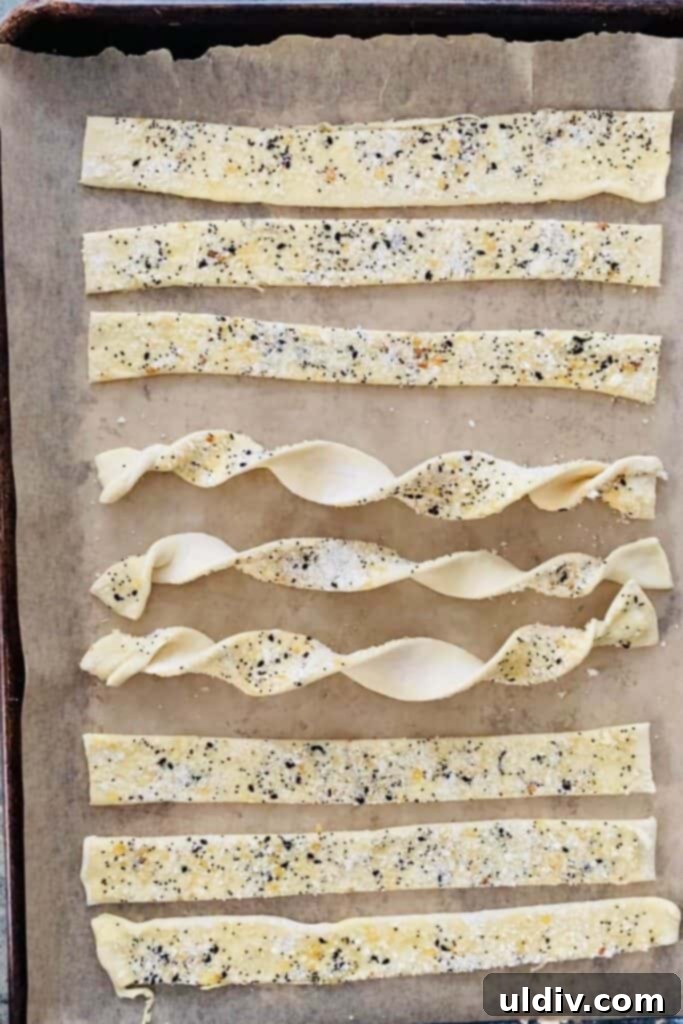 Flaky Everything Bagel Cheese Twists 8 Untwisted cheese twists laid out on a baking sheet before baking.