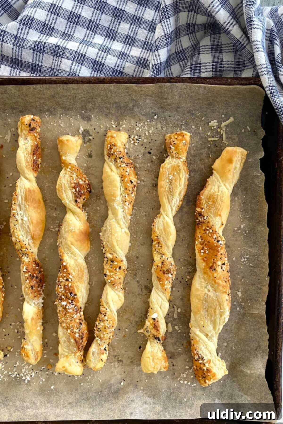 Flaky Everything Bagel Cheese Twists 10 Freshly baked crispy cheese twists on a parchment-lined baking sheet.