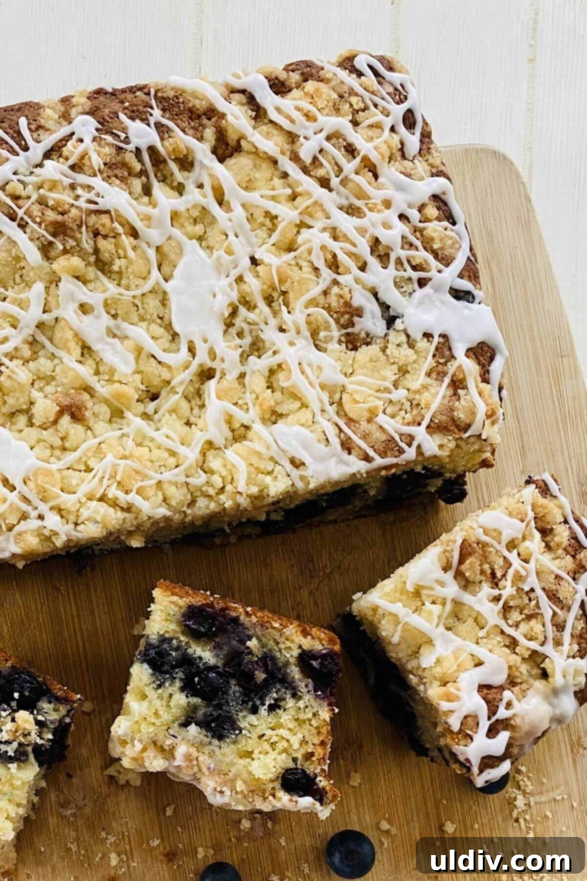 Bursting Blueberry Muffin Cake 11 Three perfectly cut slices of blueberry cake on a wire rack, ready to be enjoyed.