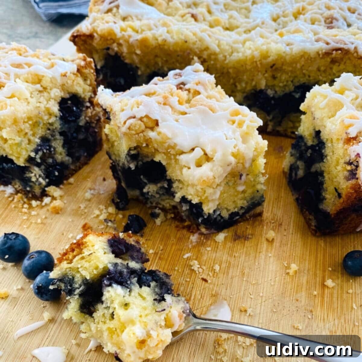 Slices of blueberry muffin cake and a fork, highlighting its texture.