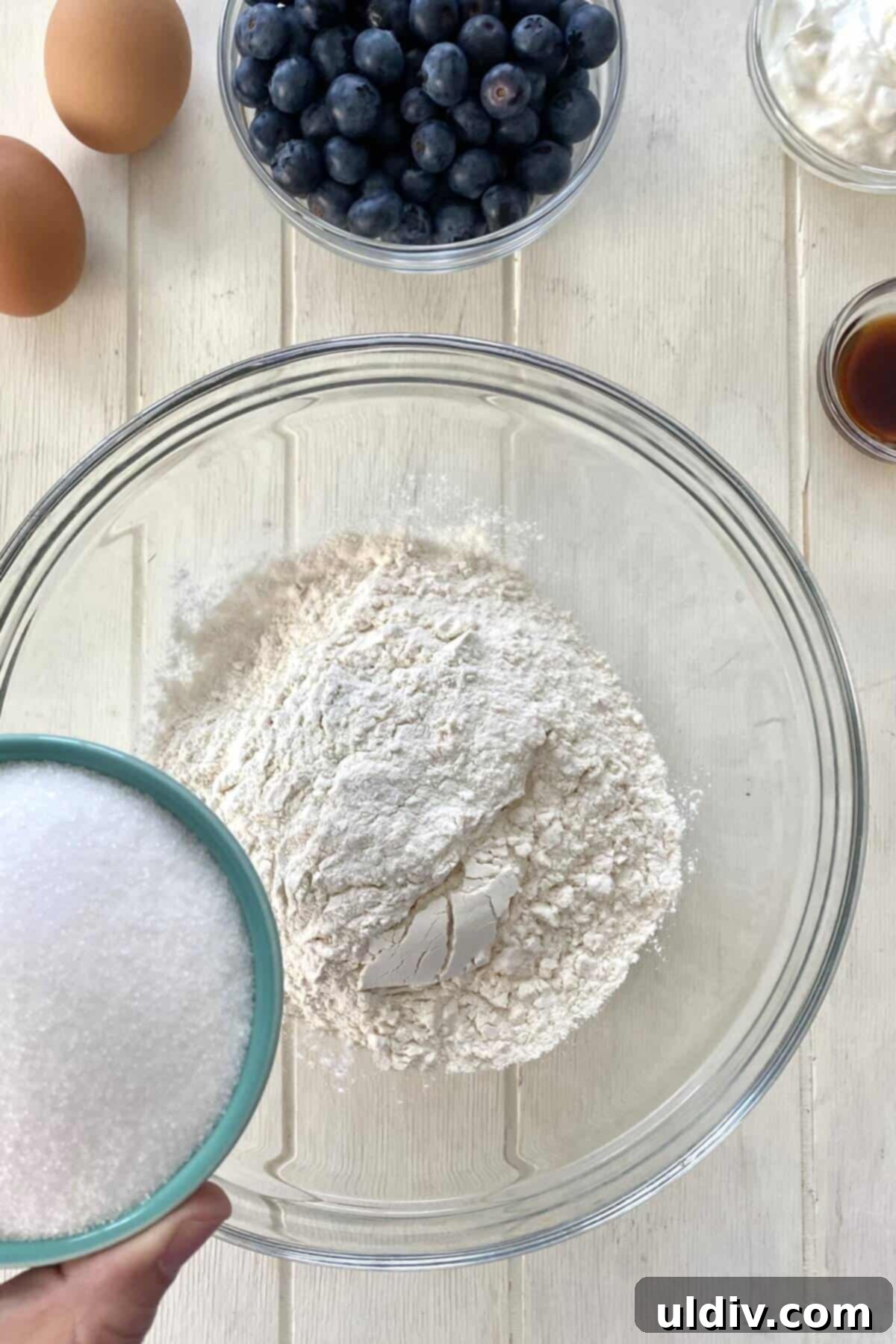 Combining dry ingredients for the blueberry muffin cake recipe in a large mixing bowl.
