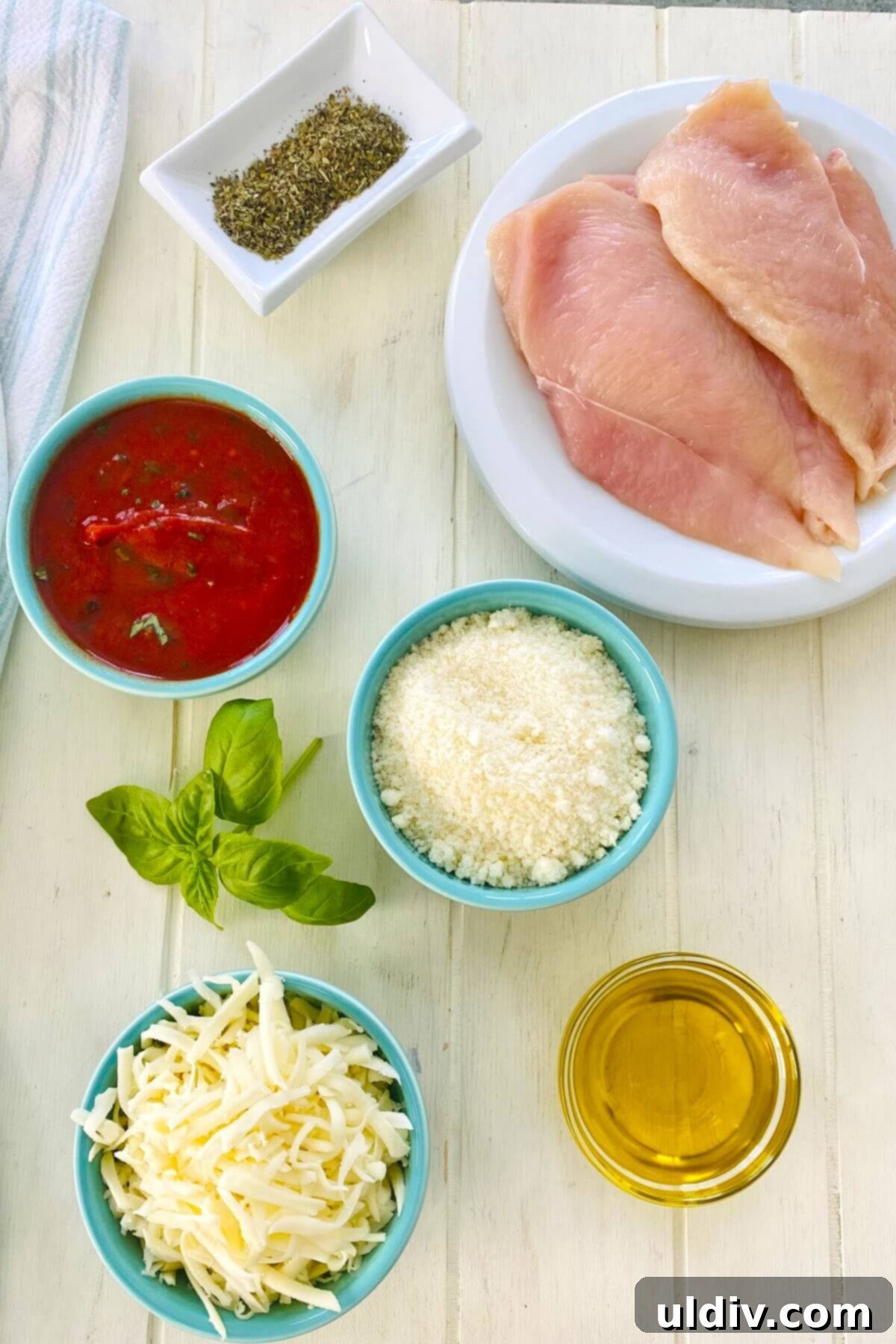 Quick and Healthy 20-Minute Low-Carb Chicken Parmesan 4 A collection of fresh ingredients for low carb chicken parmesan, including marinara sauce, basil, parmesan cheese, mozzarella cheese, and chicken breast.