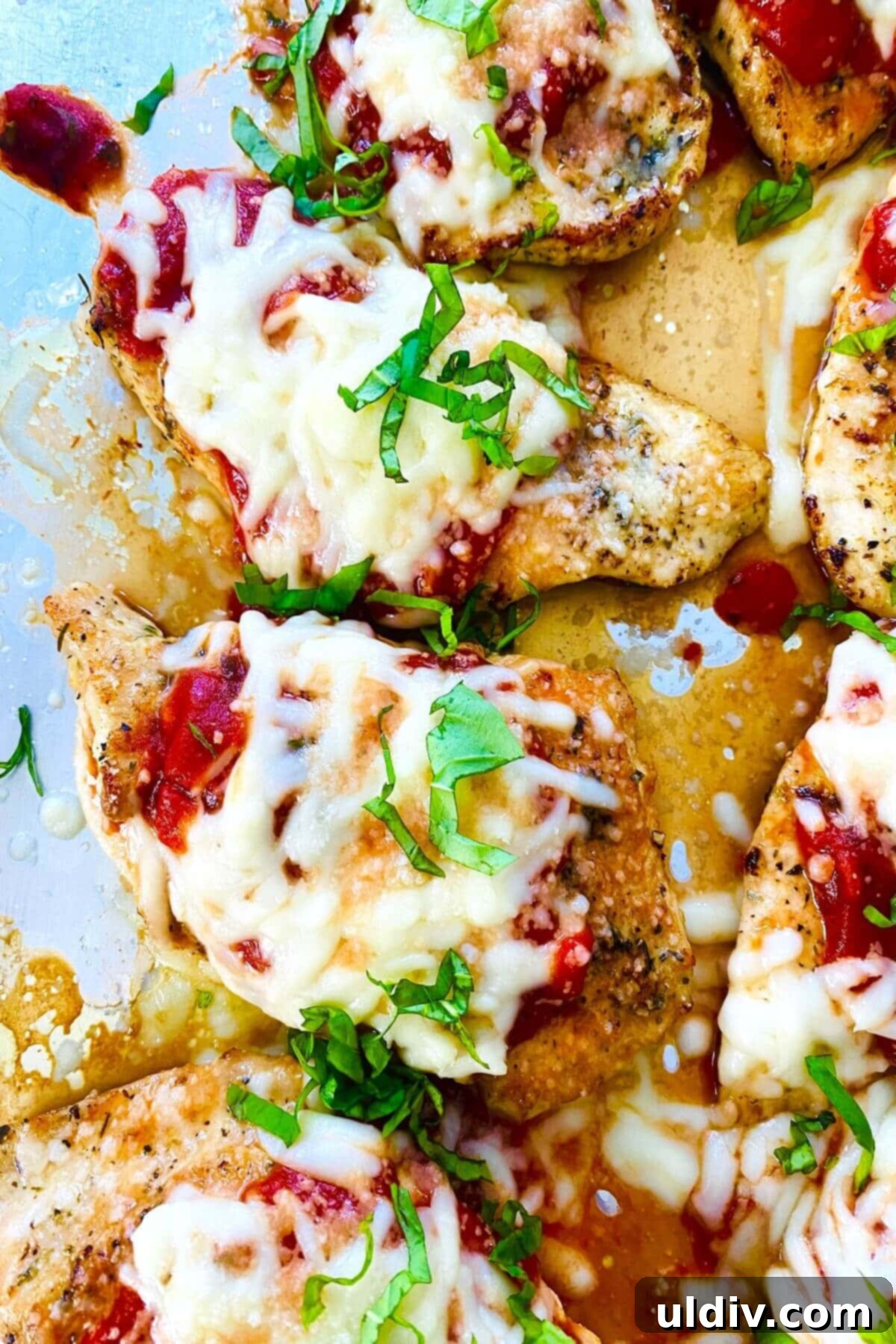 Keto chicken parmesan baked on a baking sheet with melted cheese.