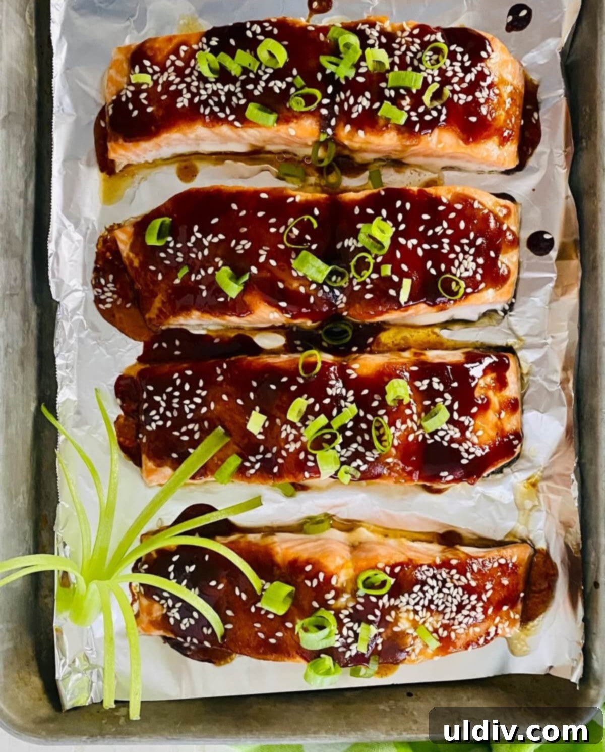Glazed Teriyaki Salmon 8 Four pieces of teriyaki glazed salmon baking in a pan in the oven.