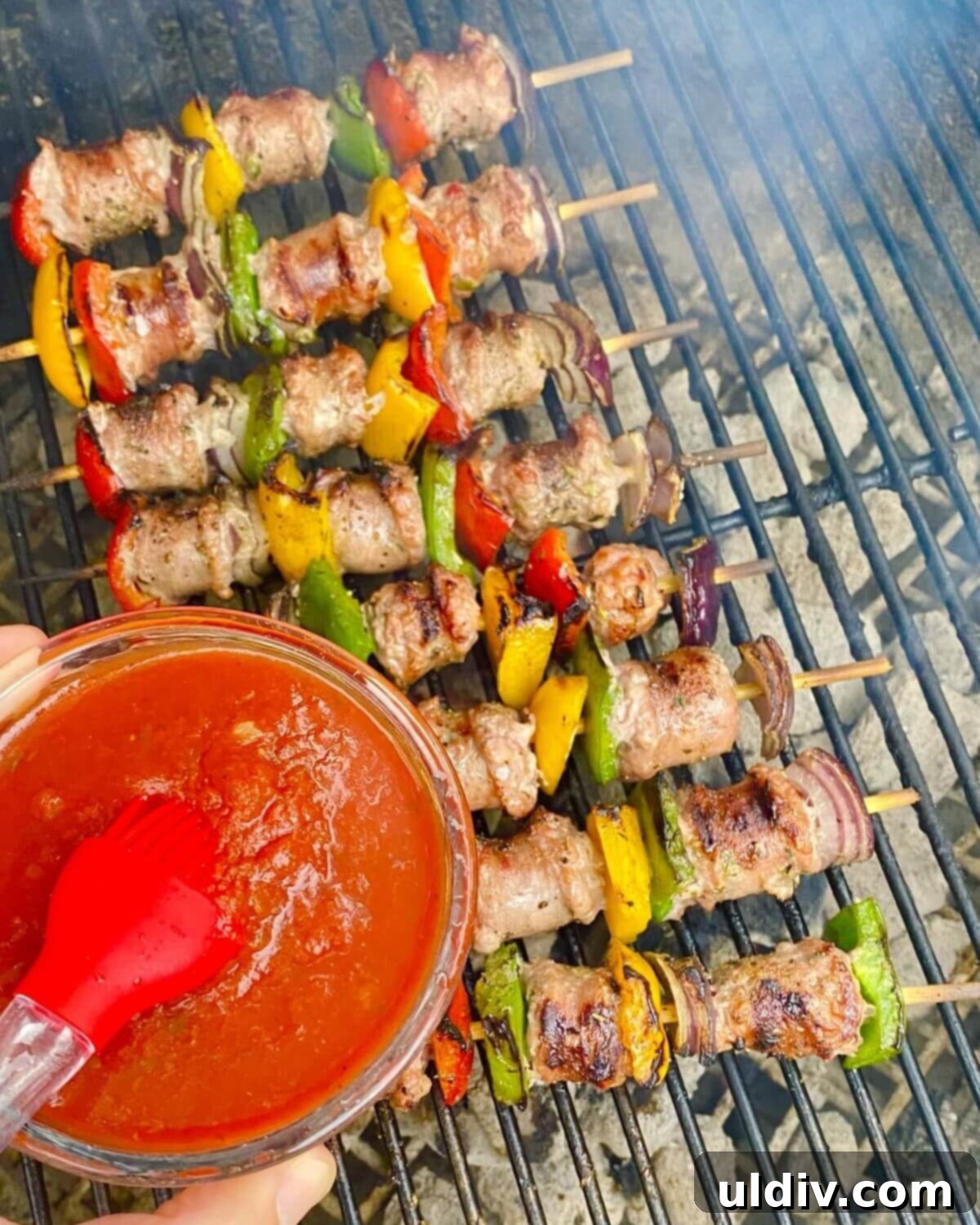 Basting grilled skewers with marinara sauce during the final minutes of cooking.
