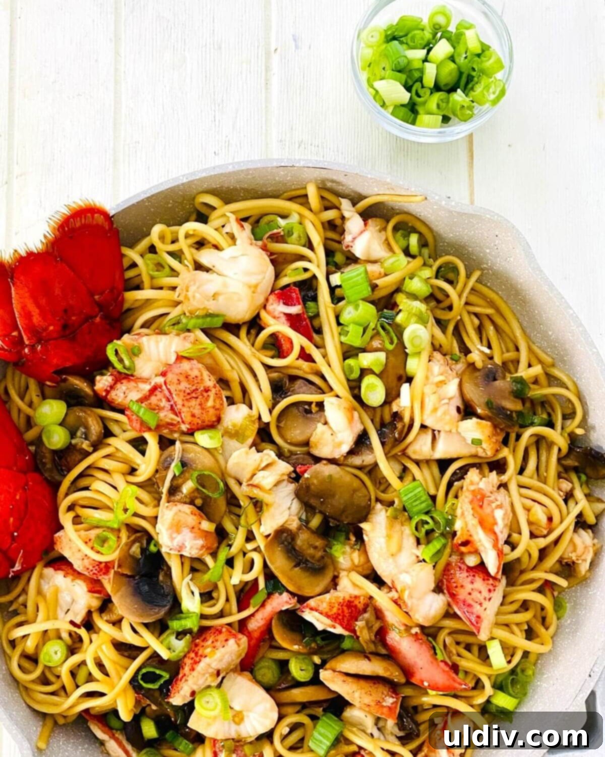 Decadent Garlic Lobster Noodles 13 Fresh green onions scattered over a pan of simmering Garlic Lobster Noodles, ready for serving.