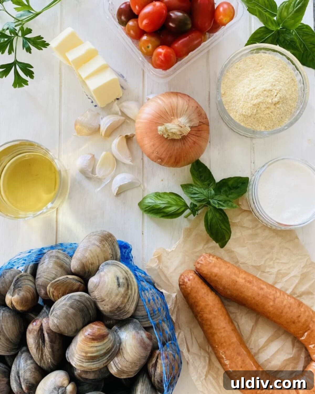 Rustic Drunken Clams with Kielbasa and Garlic 3 Littleneck clams, kielbasa, white wine, onion, garlic, basil, cornmeal, and butter laid out as ingredients.