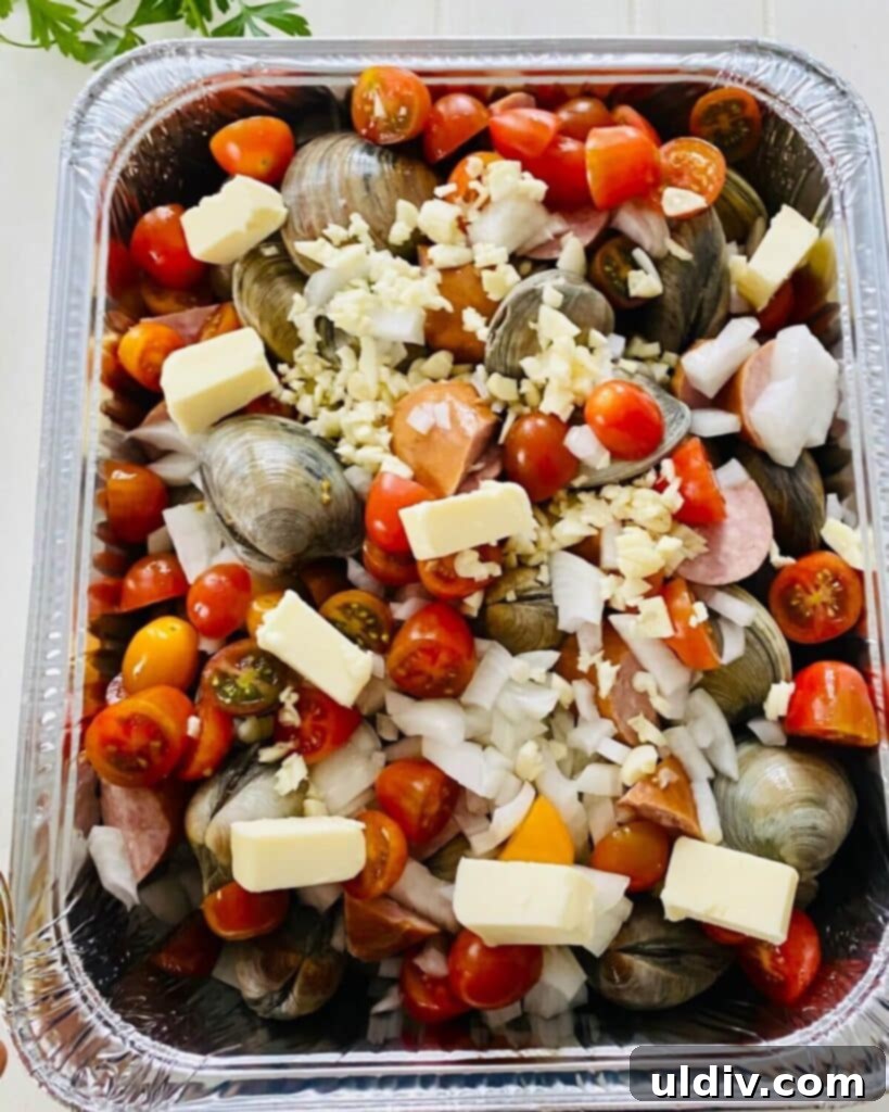 Rustic Drunken Clams with Kielbasa and Garlic 5 Clams, kielbasa, butter, onion, garlic, and tomatoes arranged in a foil pan.