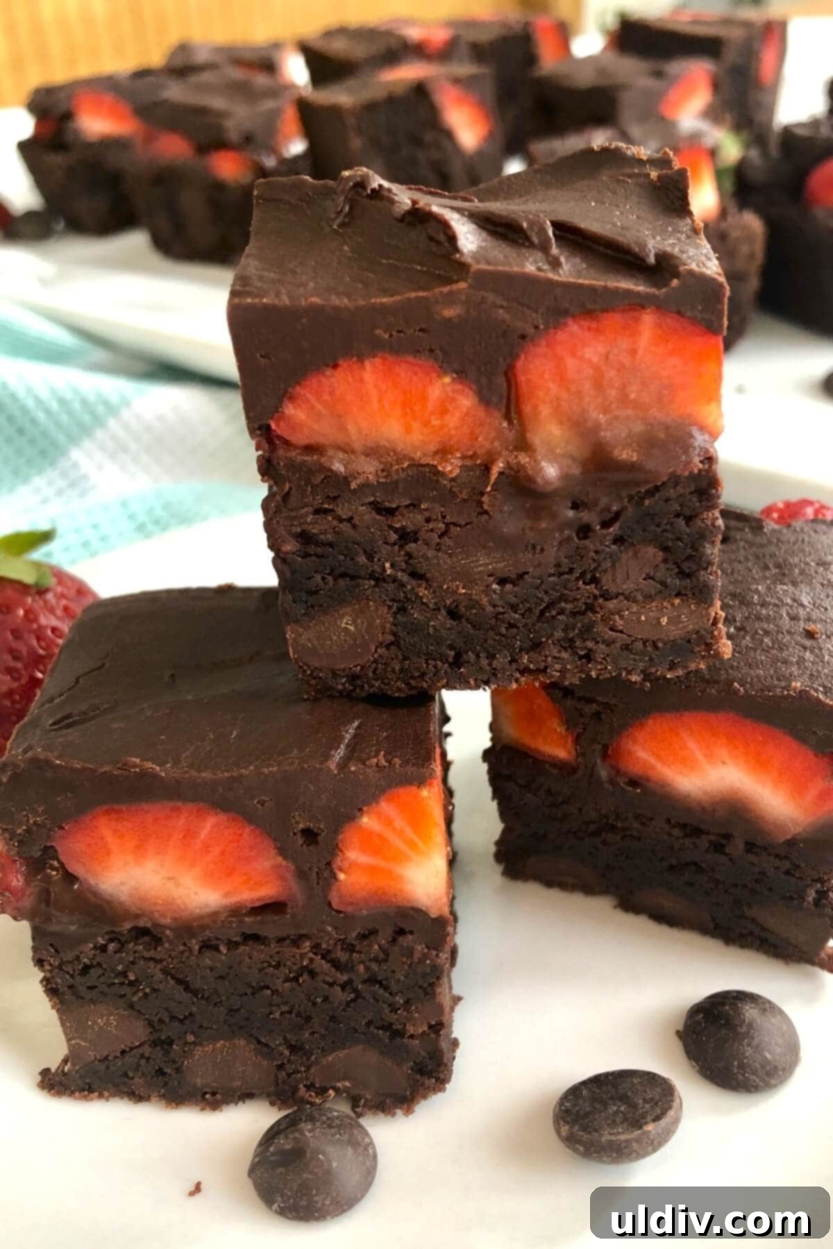 Fudgy Chocolate-Dipped Brownies with Fresh Strawberries 11 A close-up stack of three chocolate strawberry brownies, displaying the thick brownie layer, fresh strawberries, and glossy chocolate ganache.