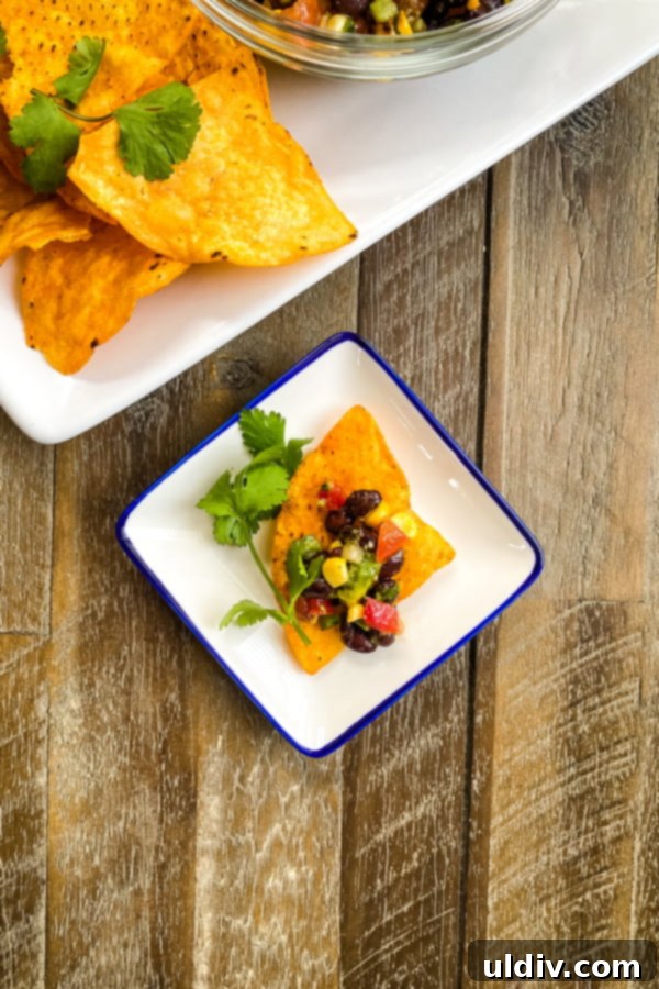 Zesty Bean and Avocado Texas Caviar 3 A single Dorito chip adorned with a generous scoop of Texas caviar bean dip, showcasing its colorful ingredients.