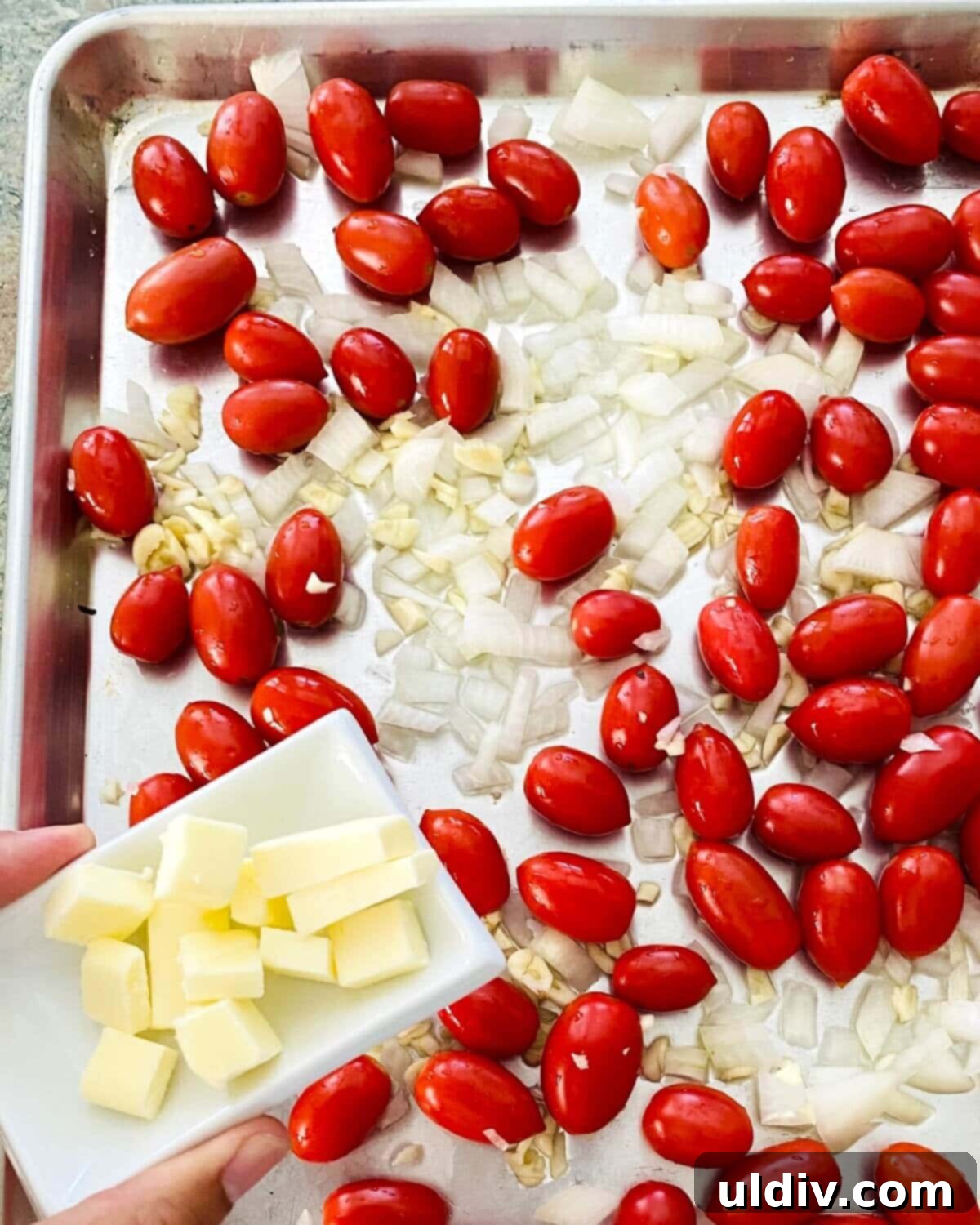 Oven-Kissed Cherry Tomato Pasta 6 adding salted butter to baking sheet with cherry tomatoes.