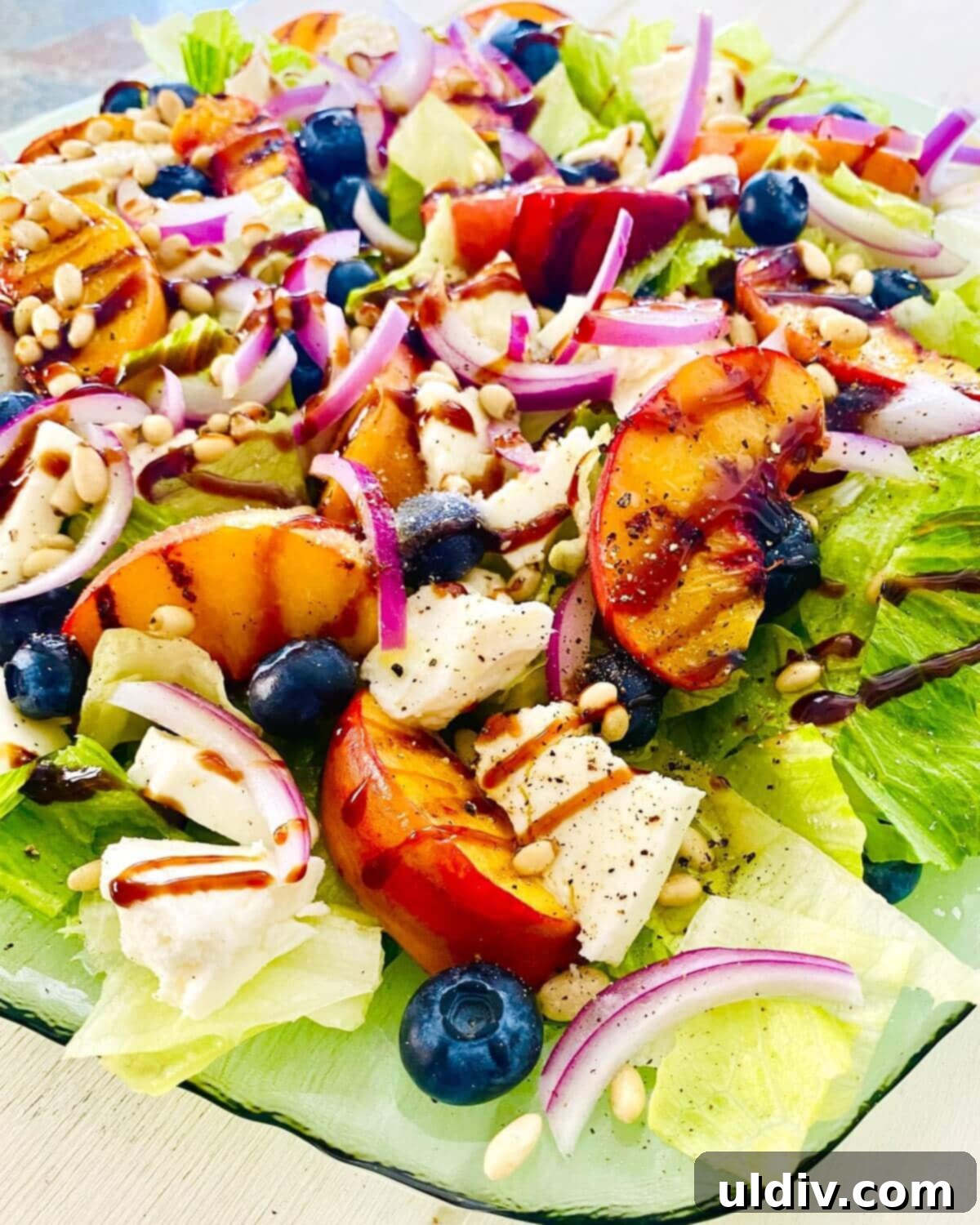 Golden Grille Peach & Creamy Mozzarella Salad 11 A beautifully presented grilled peach salad, showcasing the combination of stone fruit, mozzarella, and blueberries from an angle.