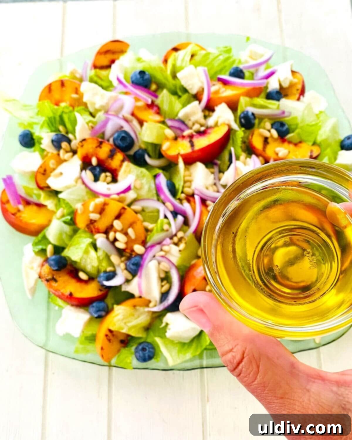 Sweet and Savory Grilled Peach Mozzarella Salad 7 Adding olive oil to a salad with grilled peaches.