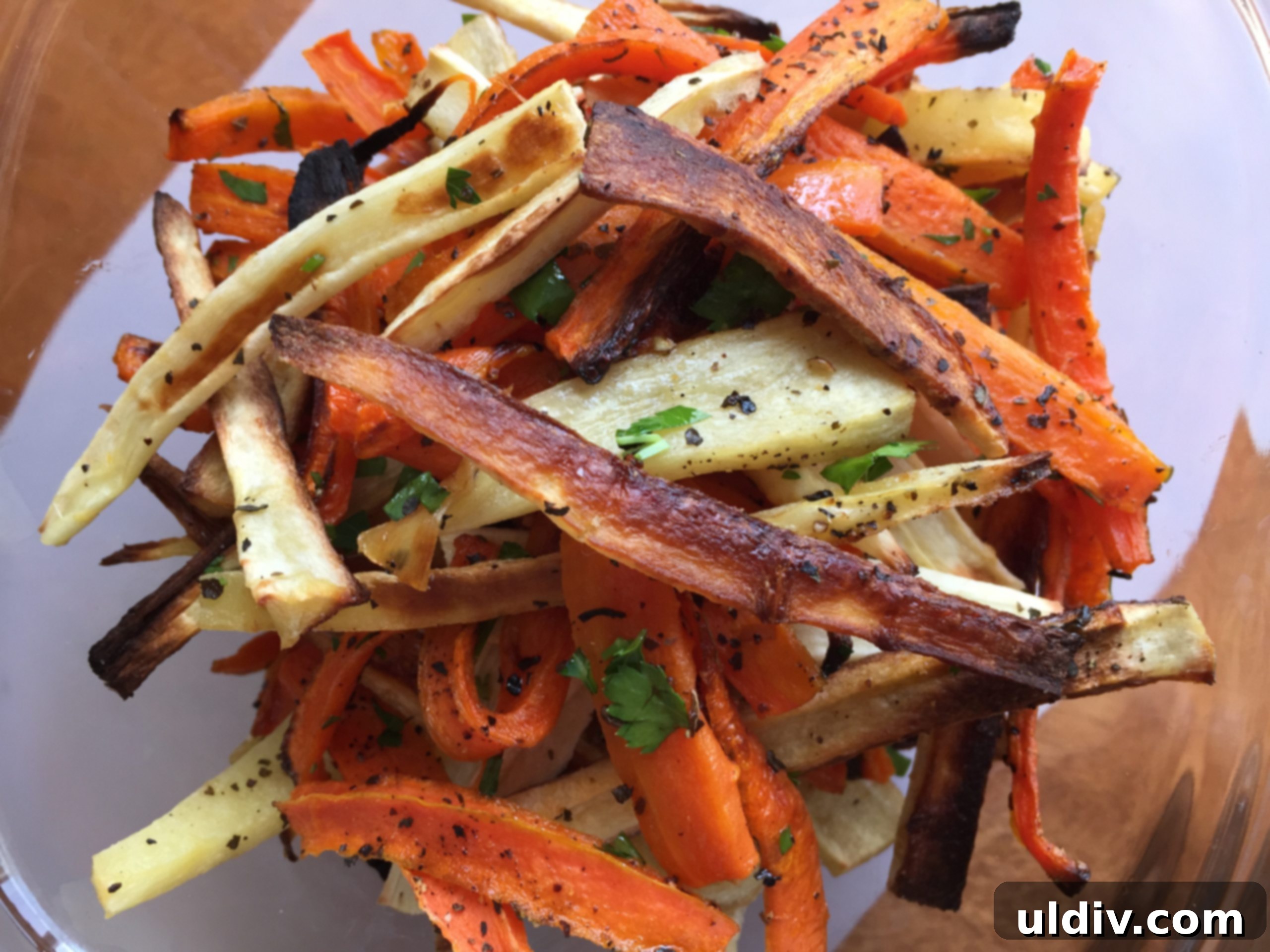 Crispy Oven-Baked Carrot and Parsnip Sticks 5 A plate of golden-brown, crispy roasted carrot and parsnip fries, garnished with fresh herbs
