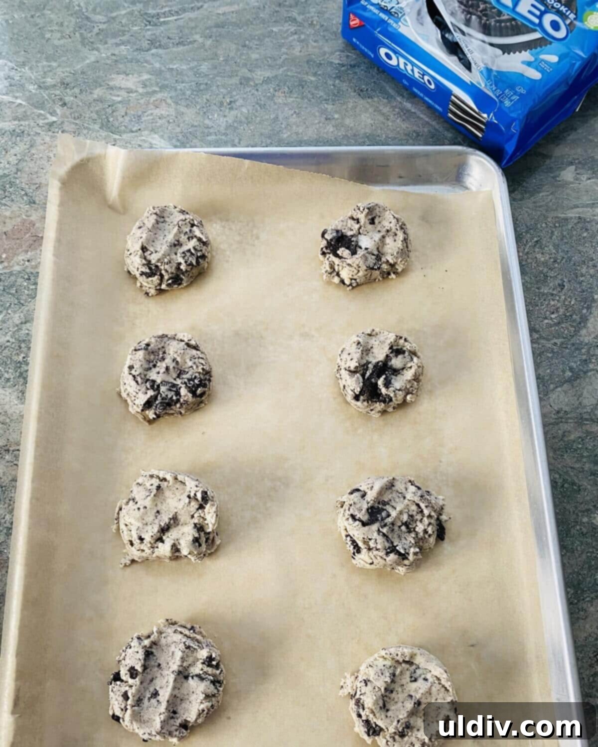 Perfectly Shaped Oreo Sugar Cookies 8 Oreo sugar cookie dough balls evenly spaced on a parchment-lined baking sheet, ready for the oven.