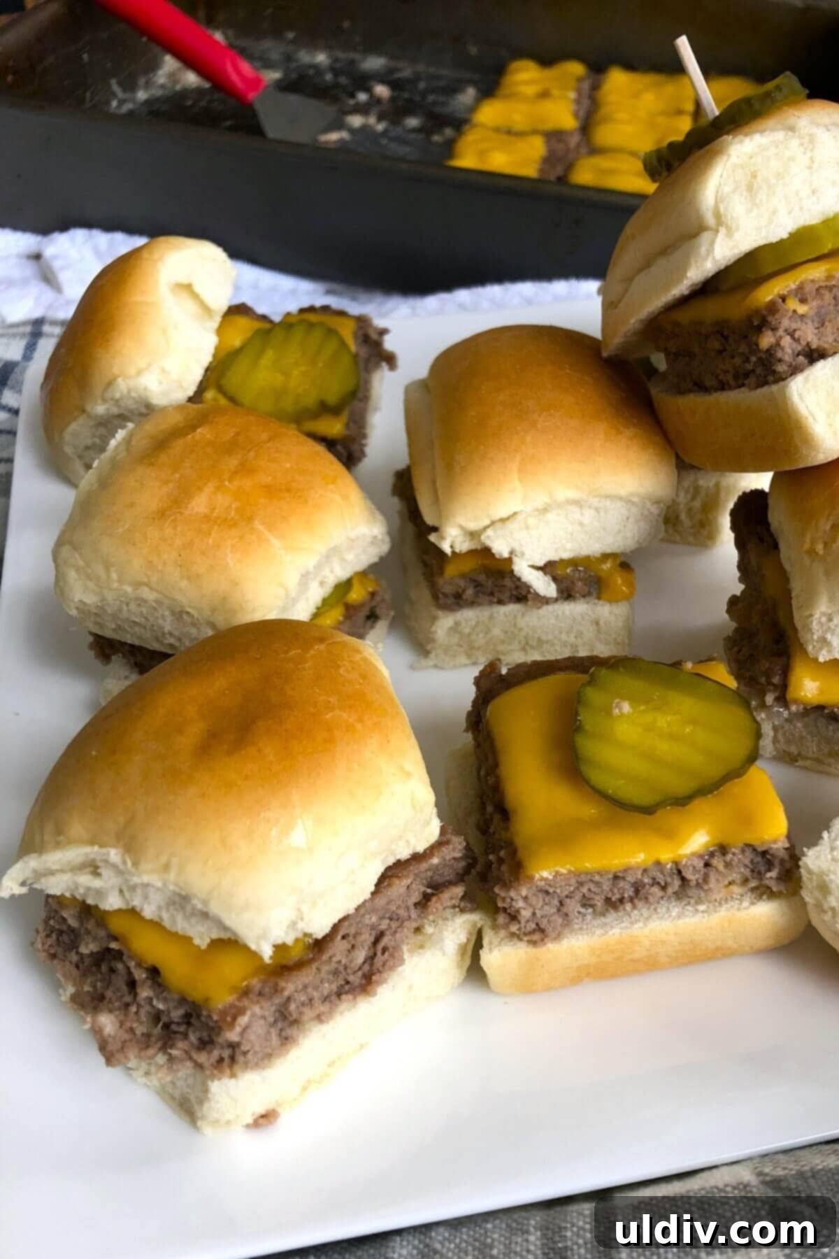 Ultimate Crowd-Pleasing Cheeseburger Sliders 11 A stack of cheeseburger sliders on a white plate, ready to be served.